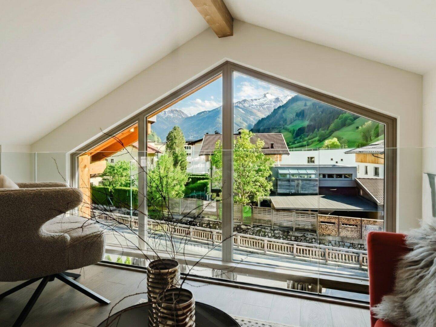 Helles Wohnzimmer mit großen Fenstern und atemberaubendem Blick auf die umliegende Berglandschaft.