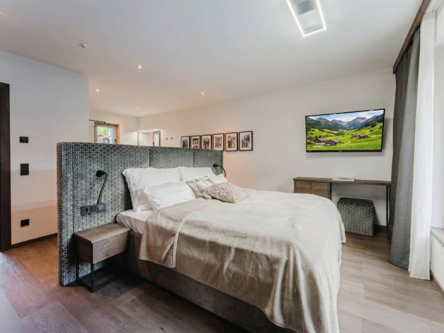 Geräumiges Schlafzimmer mit großem Bett, Wandfernseher und modernem Design für Komfort.