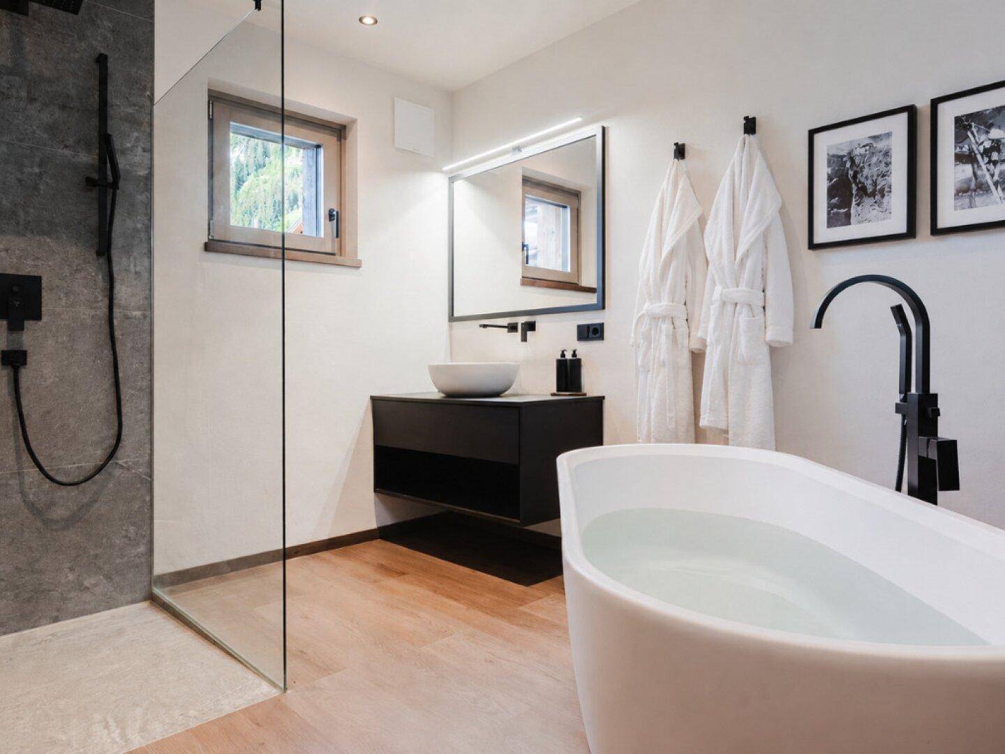 Modernes Badezimmer mit freistehender Badewanne, begehbarer Dusche und Fenster für Tageslicht.
