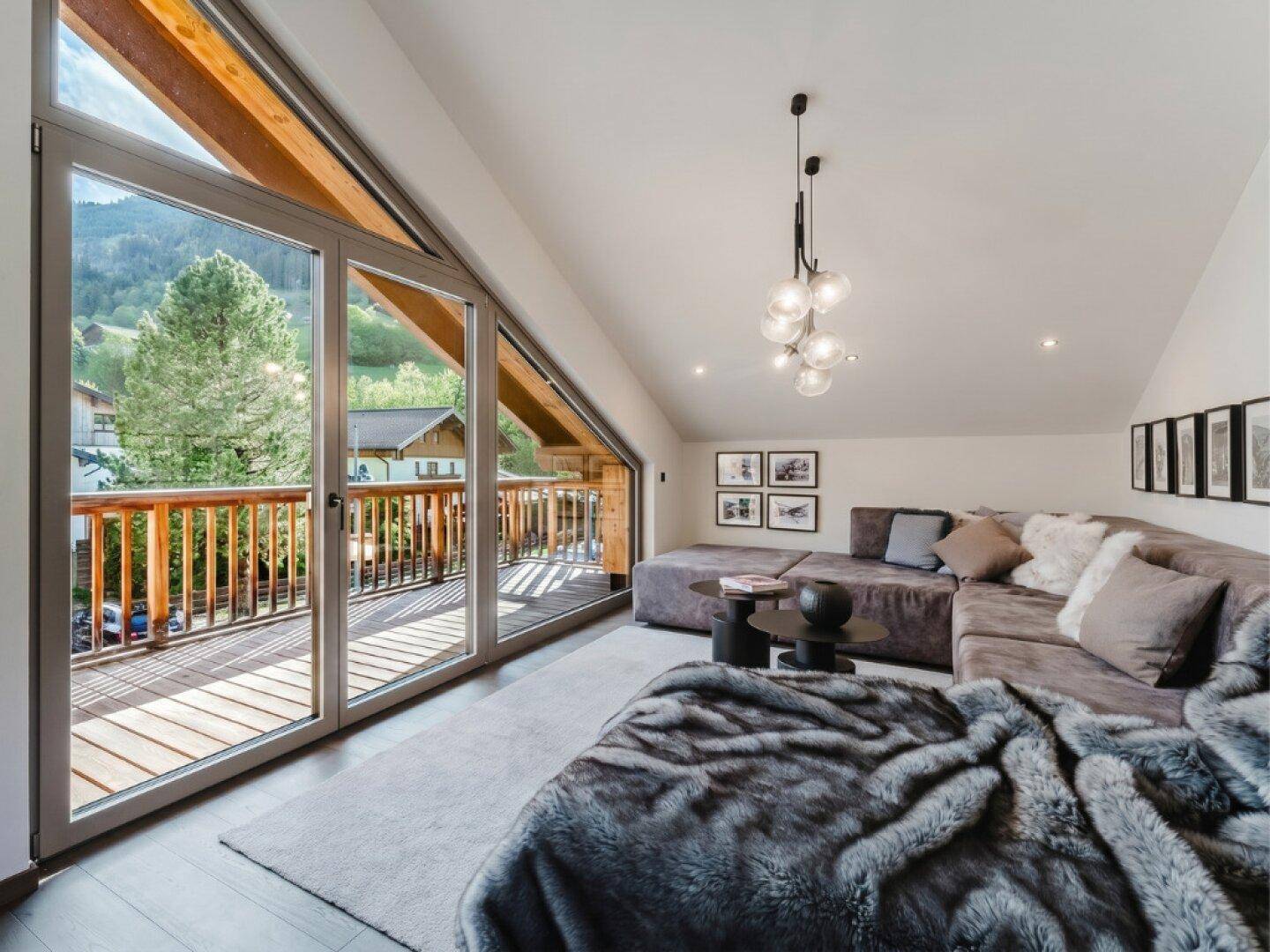 Gemütlicher Wohnbereich mit großem Sofa und Balkonzugang, ideal zum Entspannen mit Bergblick.