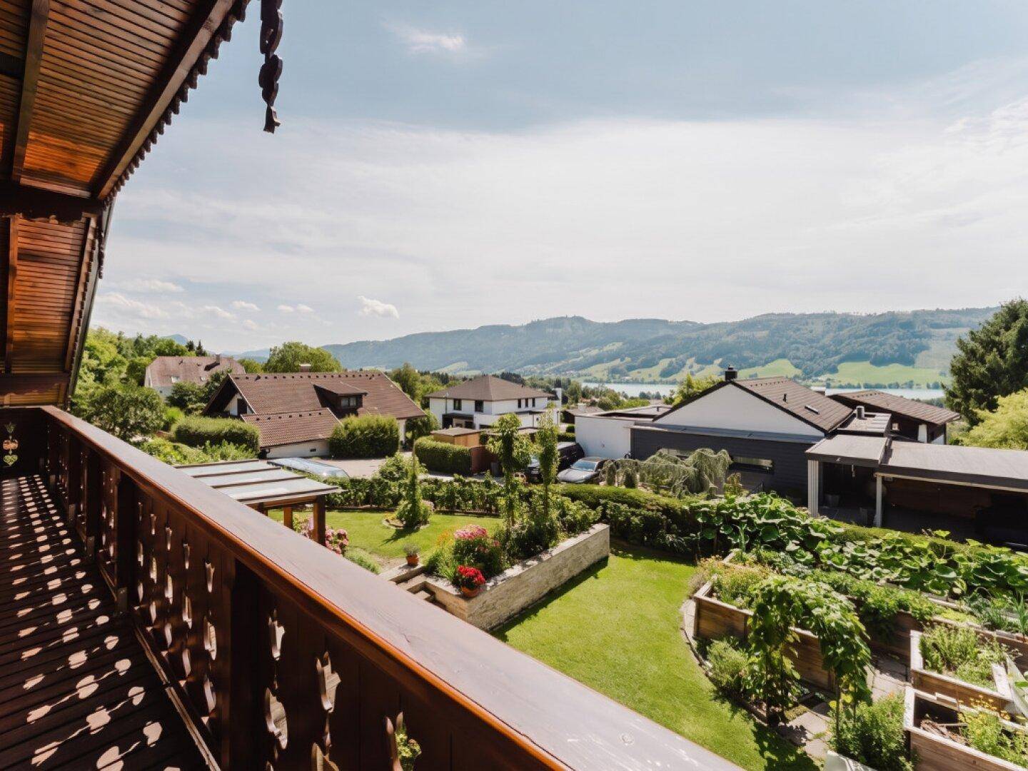 Weitläufiger Ausblick vom Balkon über die grüne Landschaft und einen See in der Ferne.