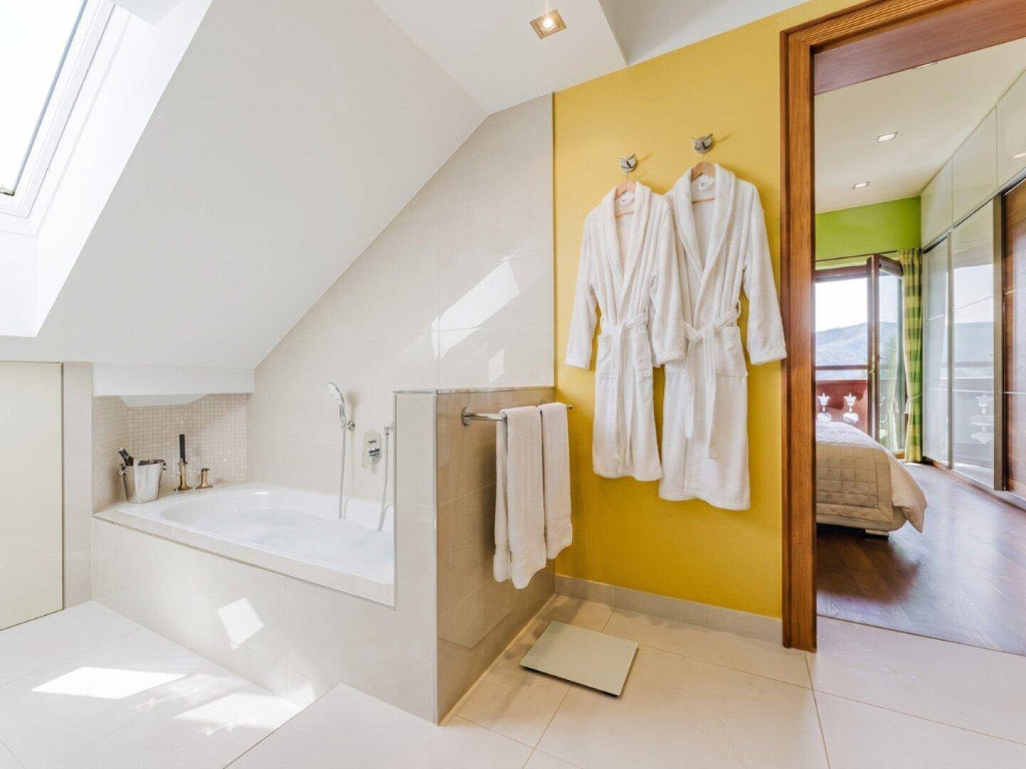 Helles Badezimmer im Dachgeschoss mit Badewanne, Dachfenster und Zugang zum Schlafzimmer.