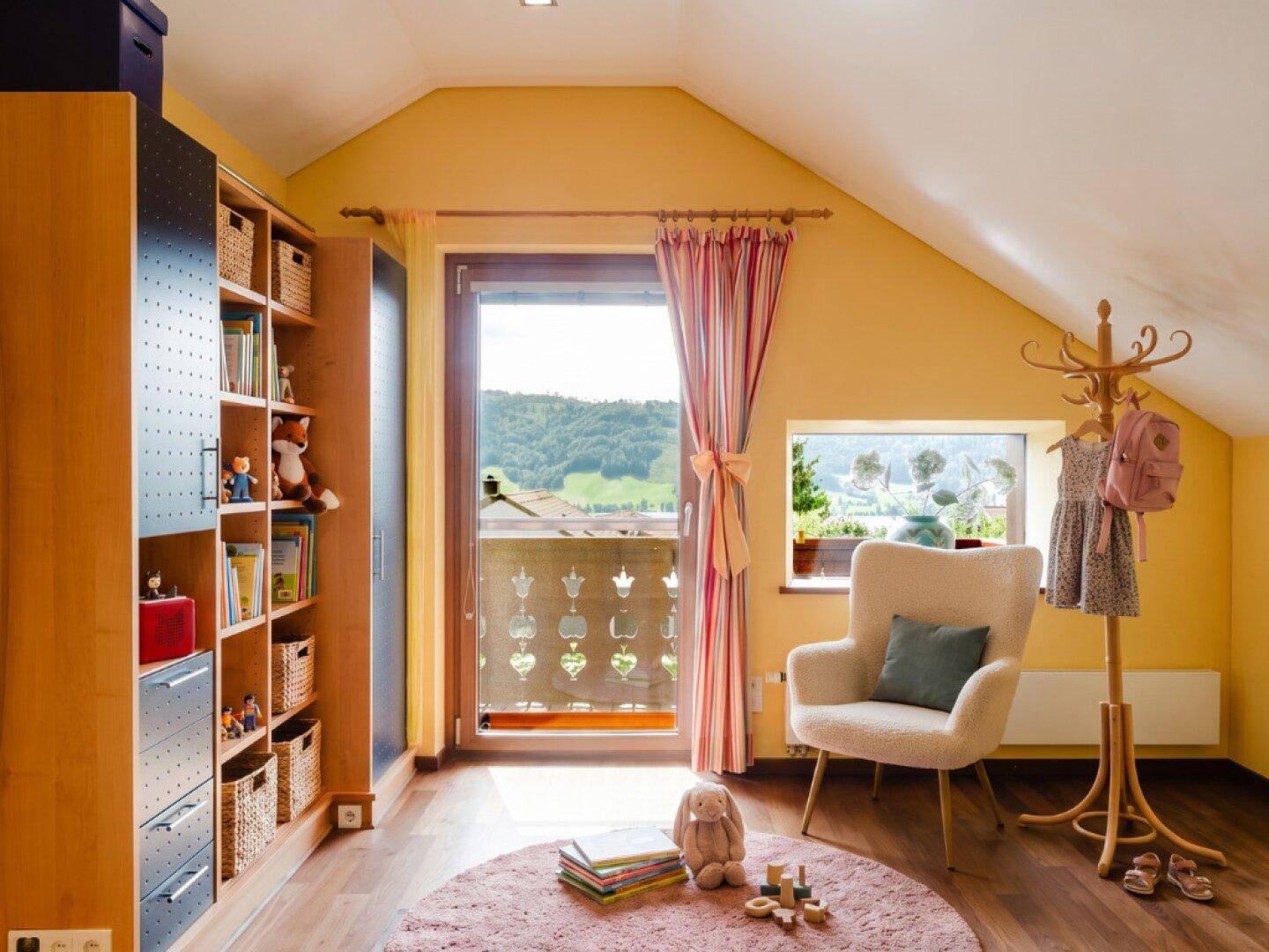 Gemütliches Schlafzimmer im Dachgeschoss mit Balkonzugang und Blick auf die Landschaft.