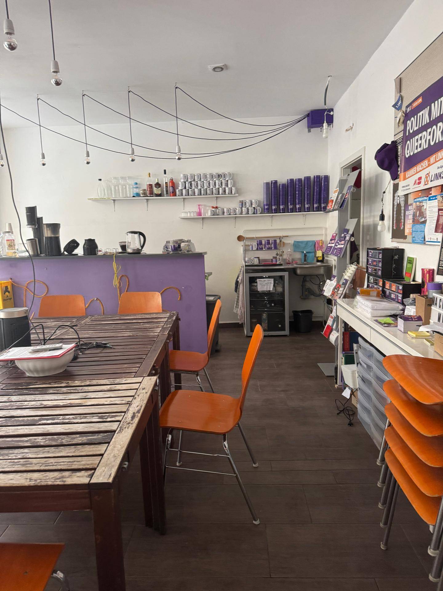 Geräumiger Büroraum mit Holztisch, orangefarbenen Stühlen und einer lila Theke im Hintergrund.