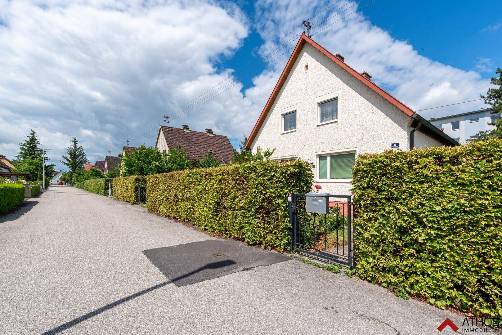 Blick auf die ruhige Wohnstraße mit dem Haus, umgeben von einer hohen, grünen Hecke.