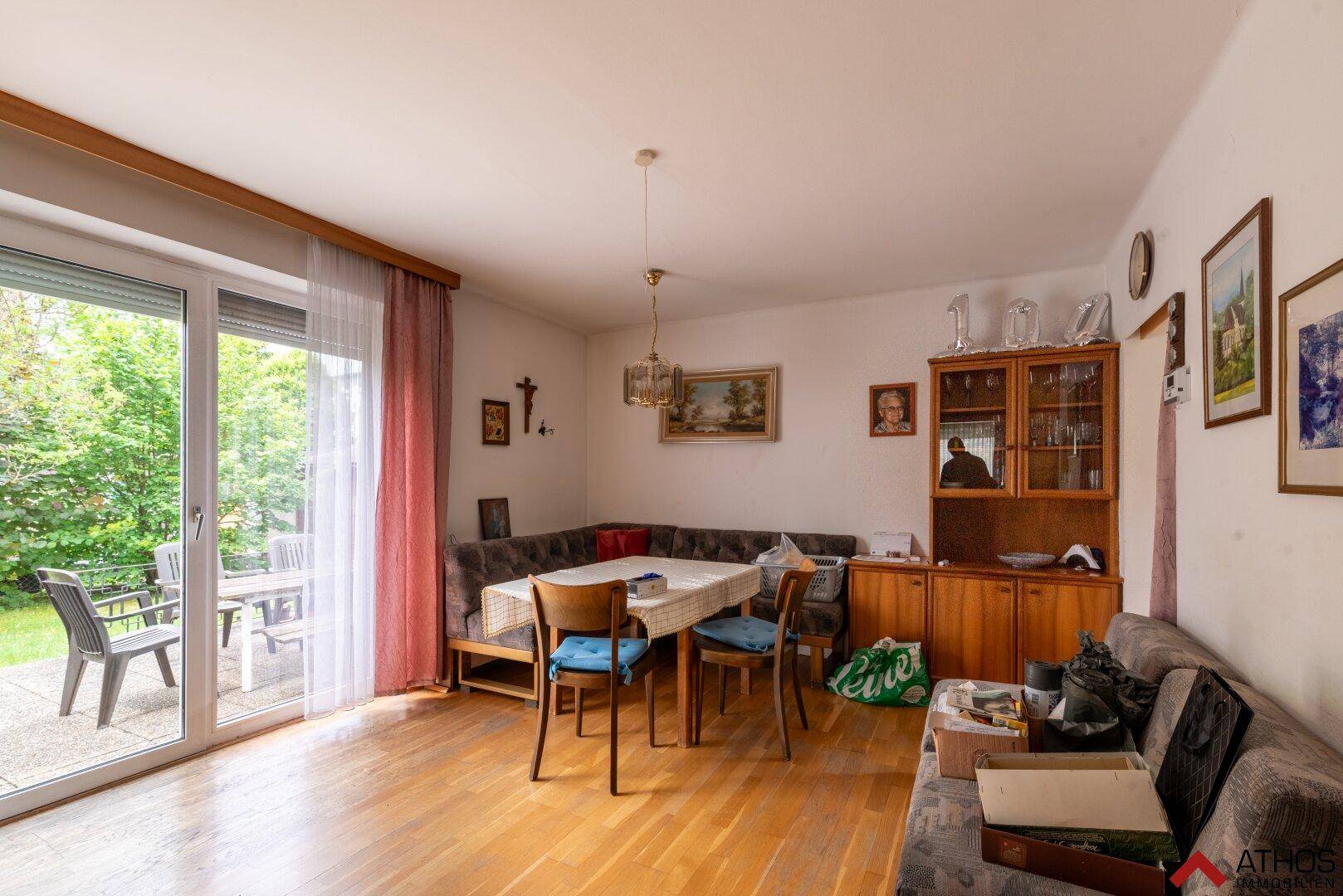 Gemütlicher Wohn- und Essbereich mit Holzboden und Zugang zur Terrasse mit Gartenblick.