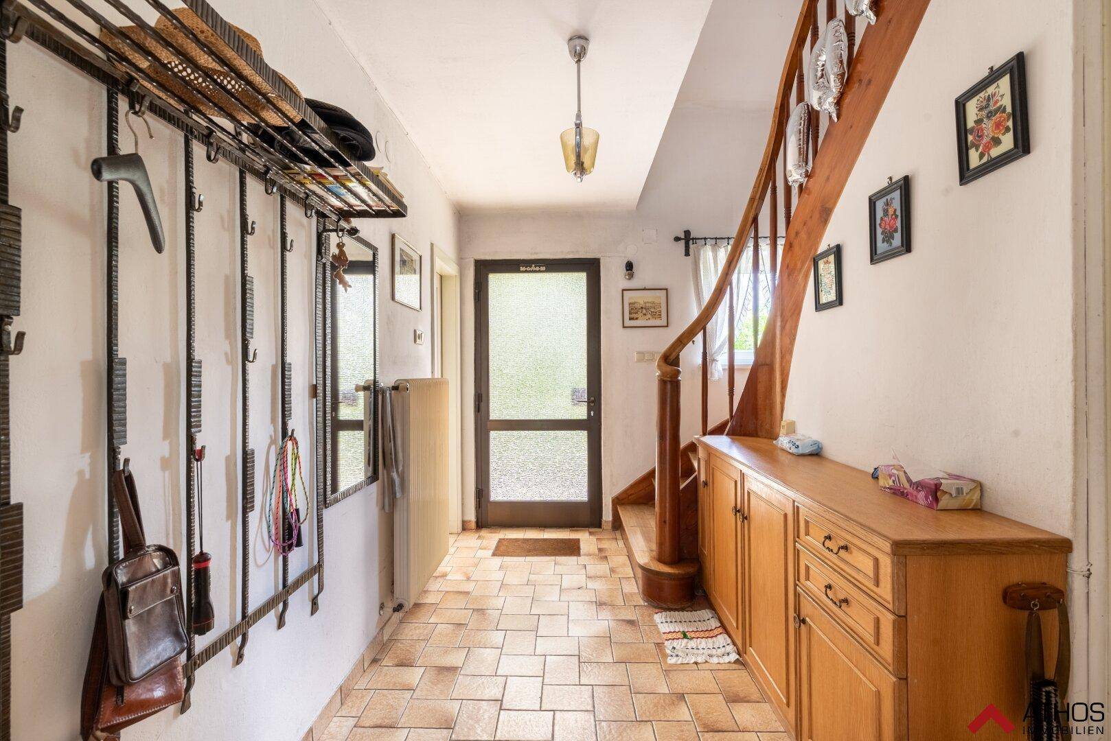 Heller Eingangsbereich mit gefliestem Boden, Holztreppe und Garderobe im traditionellen Stil.