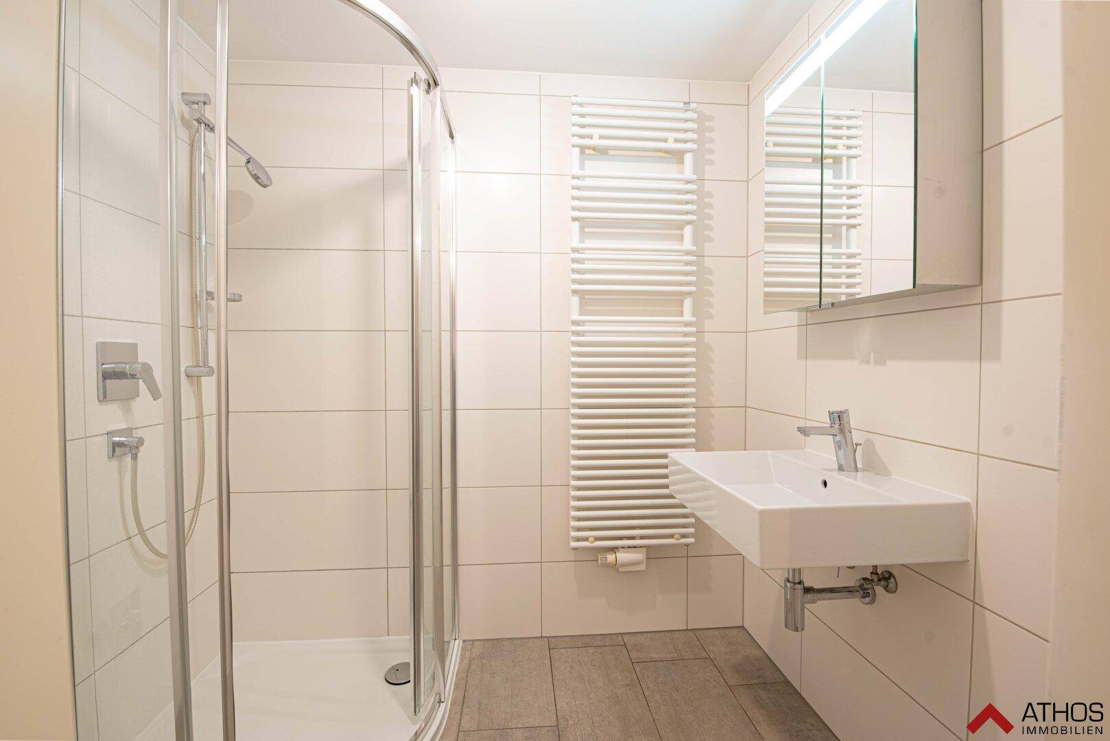 Modernes Badezimmer mit Duschkabine, Einzelwaschbecken und beheiztem Handtuchhalter.