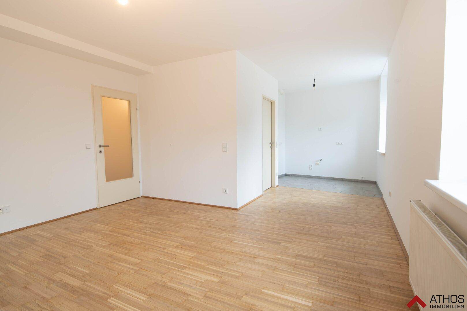 Helles Wohnzimmer mit hellem Parkettboden und weißen Wänden, bietet vielseitige Gestaltungsmöglichkeiten.