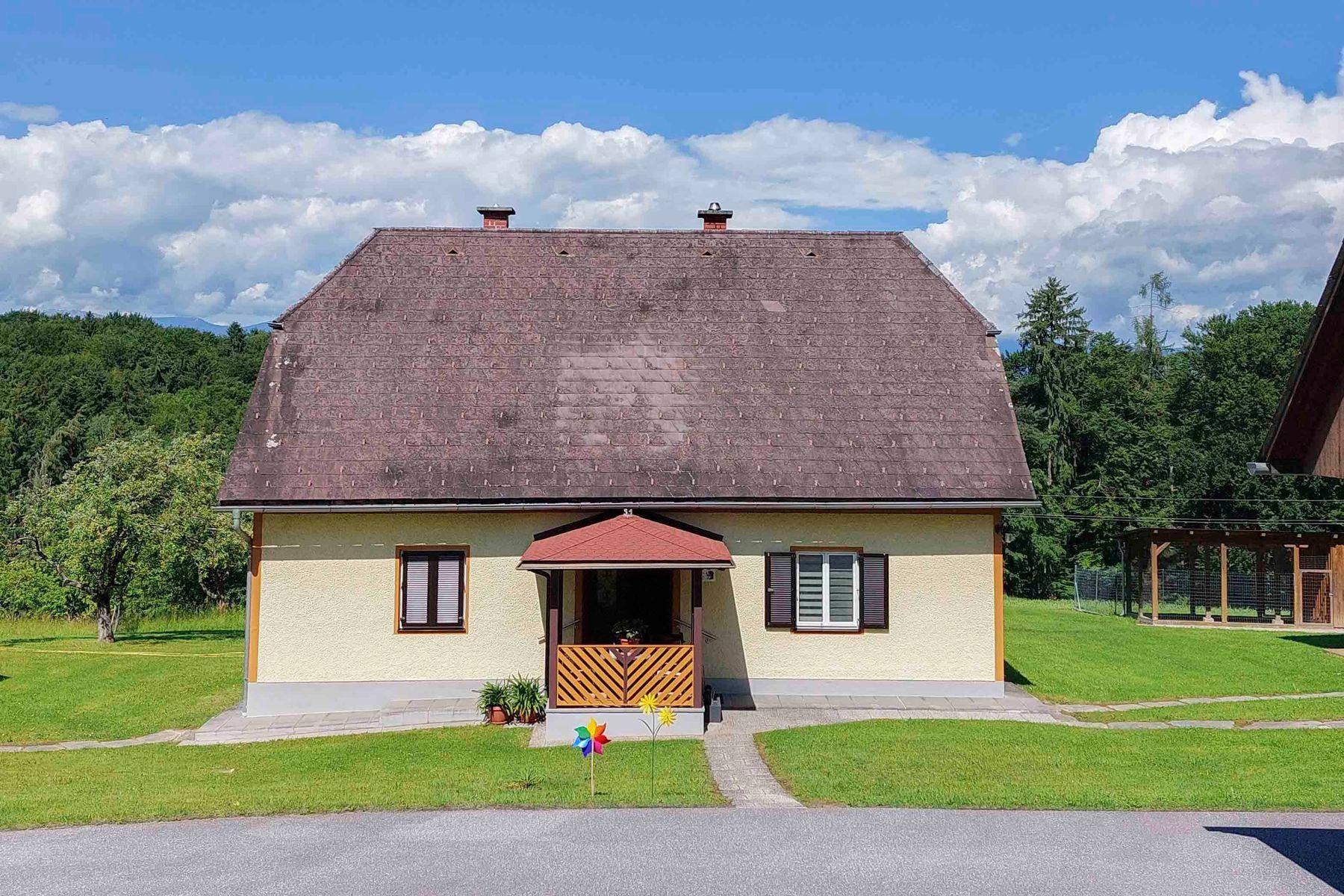 Vorderansicht des traditionellen Wohnhauses mit überdachtem Eingangsbereich und Satteldach.