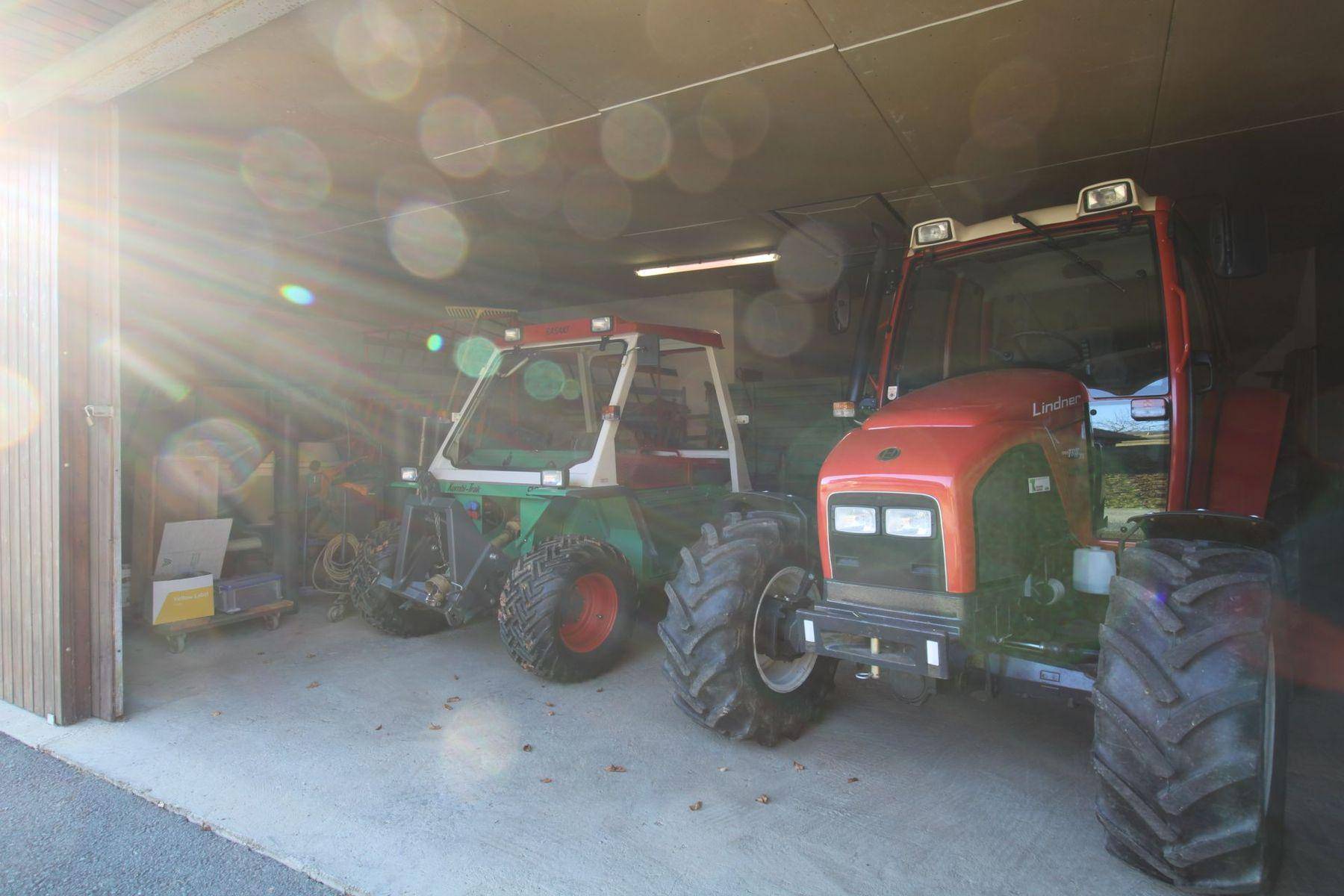 Geräumige Garage mit zwei landwirtschaftlichen Fahrzeugen und einem robusten Betonboden.