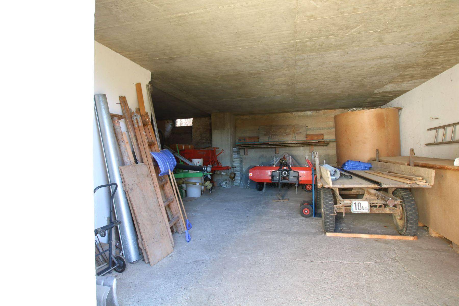 Großer Abstellraum oder Garage mit Betonboden und verschiedenen Geräten und Materialien.