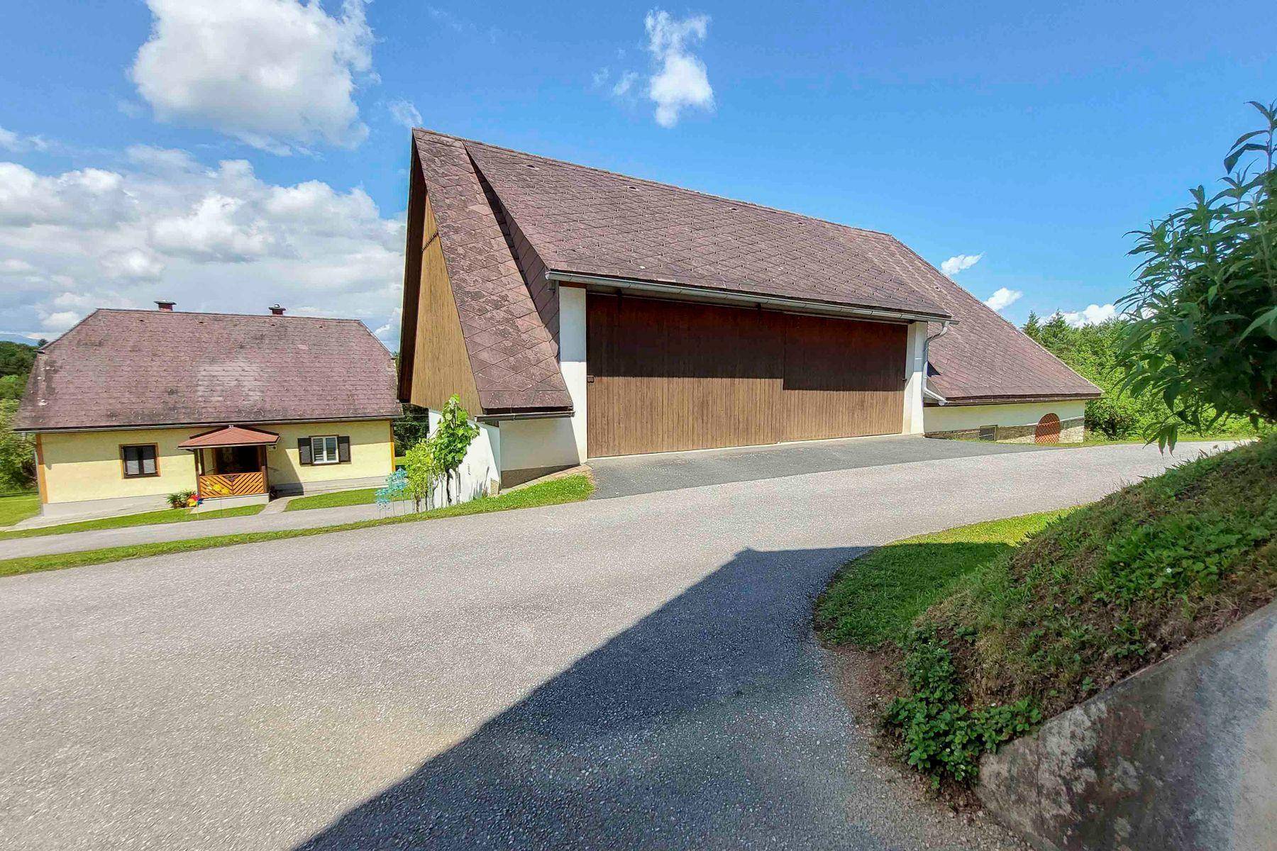 Weitläufige Ansicht von ländlichen Gebäuden mit großen Dächern und Zufahrt unter blauem Himmel.