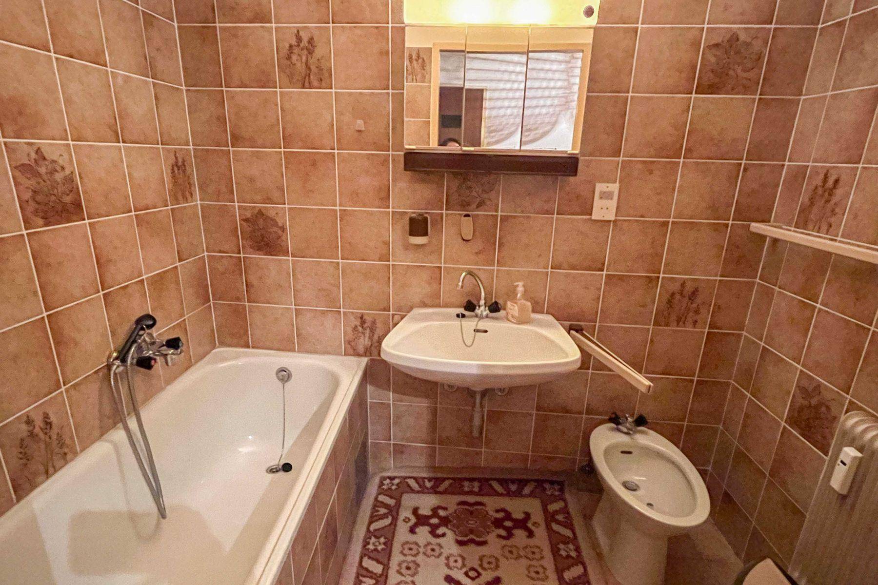 Badezimmer mit braunen Fliesen, Badewanne, Waschbecken und Bidet in traditionellem Stil.