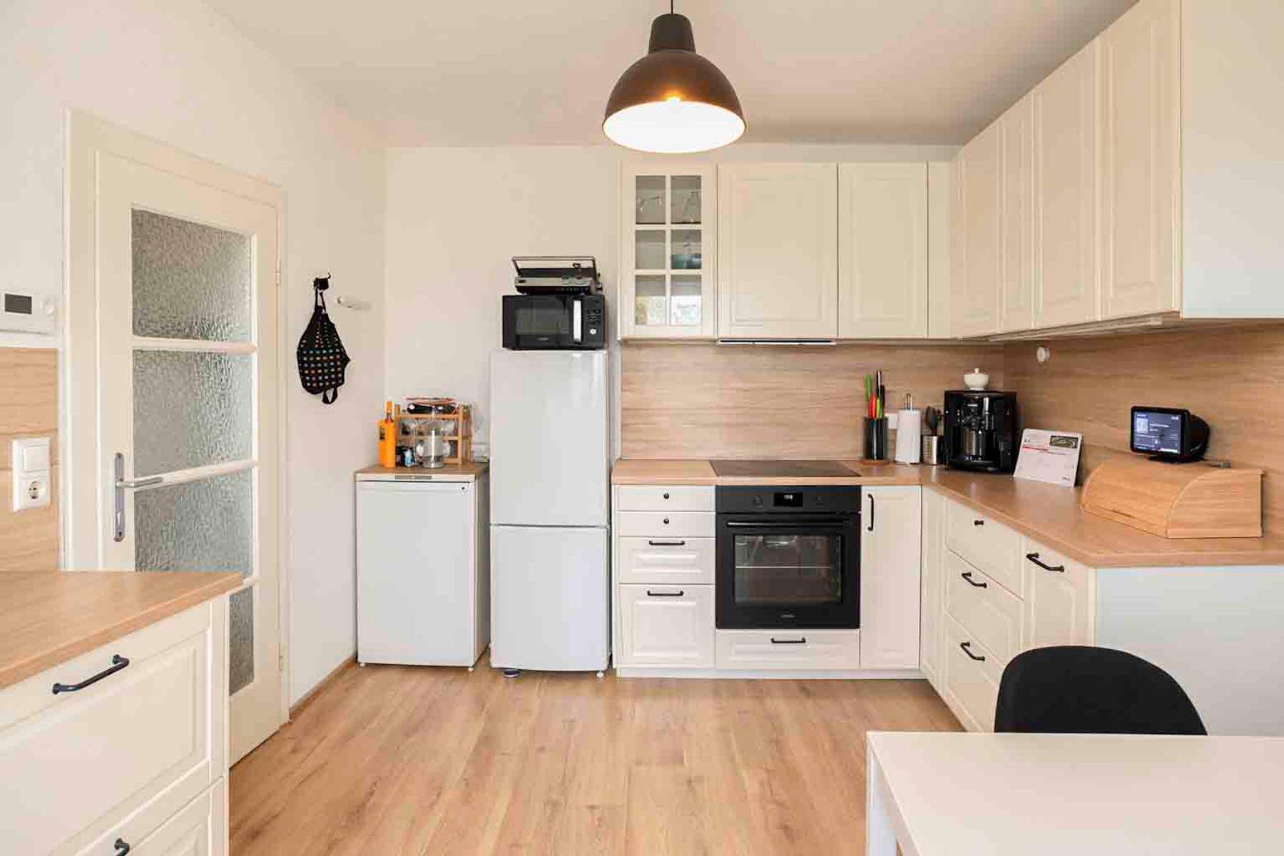 Funktionale Küche mit weißen Schränken, Holzdetails und modernen Geräten für den täglichen Gebrauch.