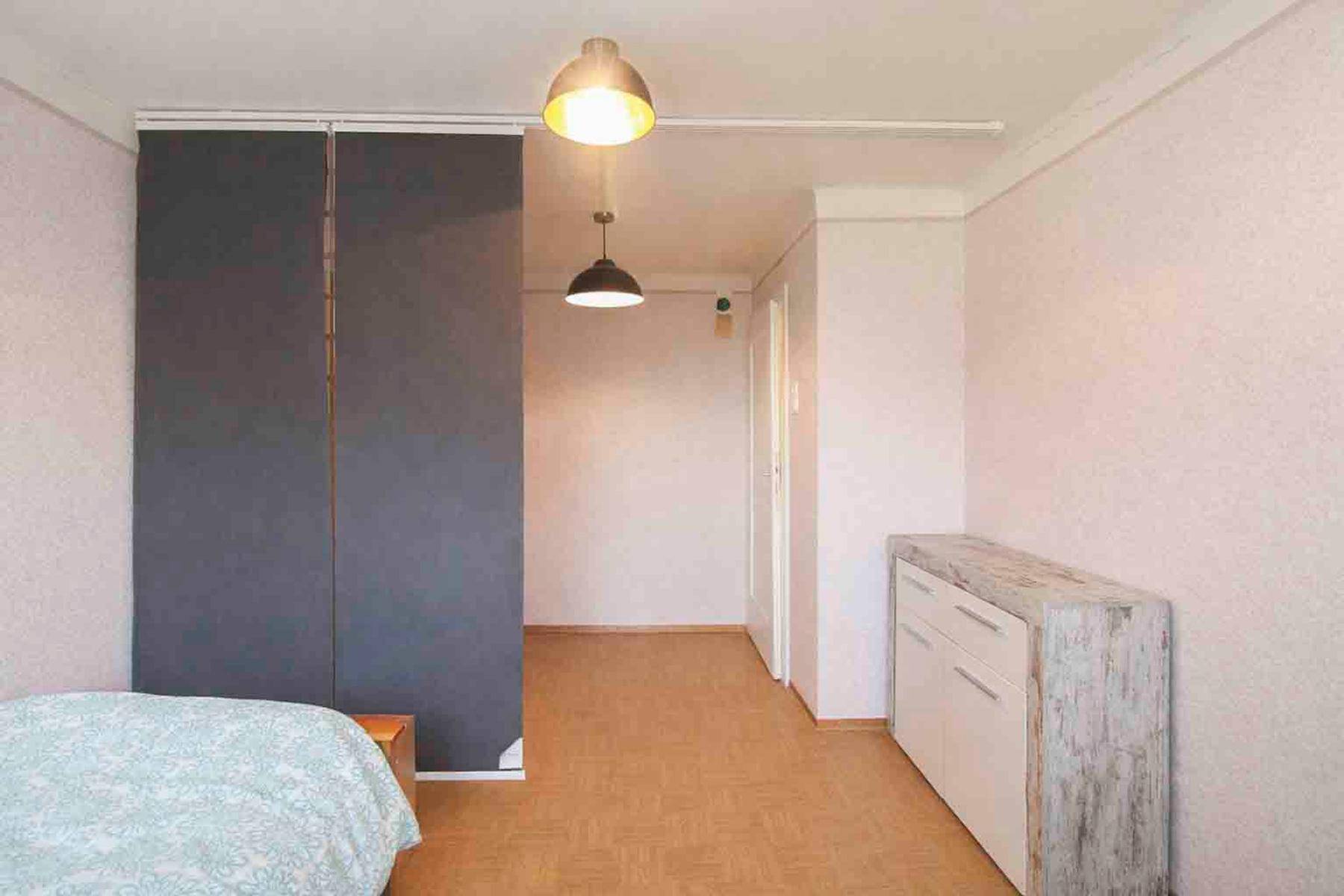 Schlafzimmer mit Raumteiler und Zugang zu einem Flur, bietet flexible Wohnlösungen.