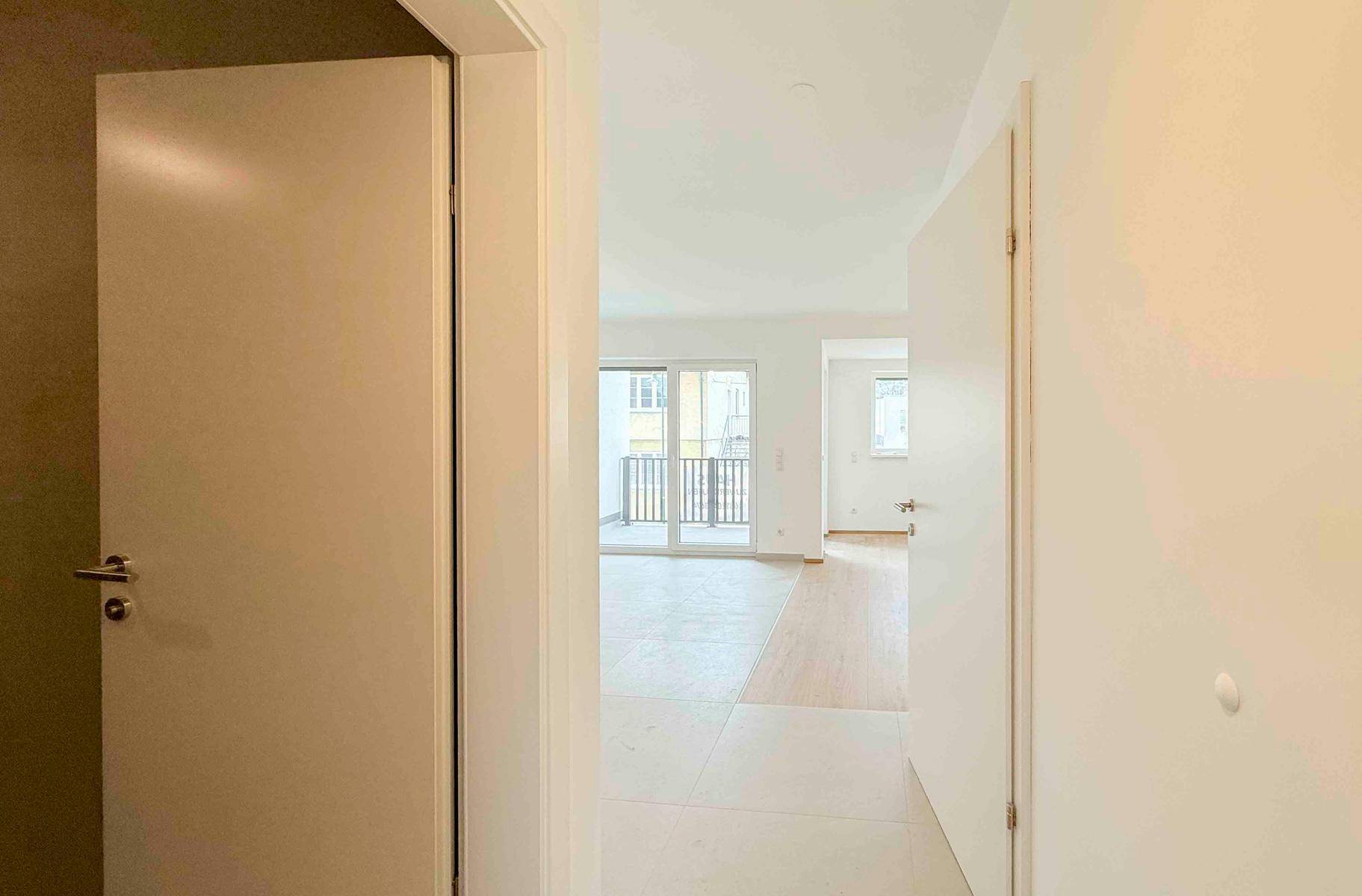 Heller Flur mit Blick in die Wohnbereiche und zum Balkon, ausgestattet mit modernen Türen.