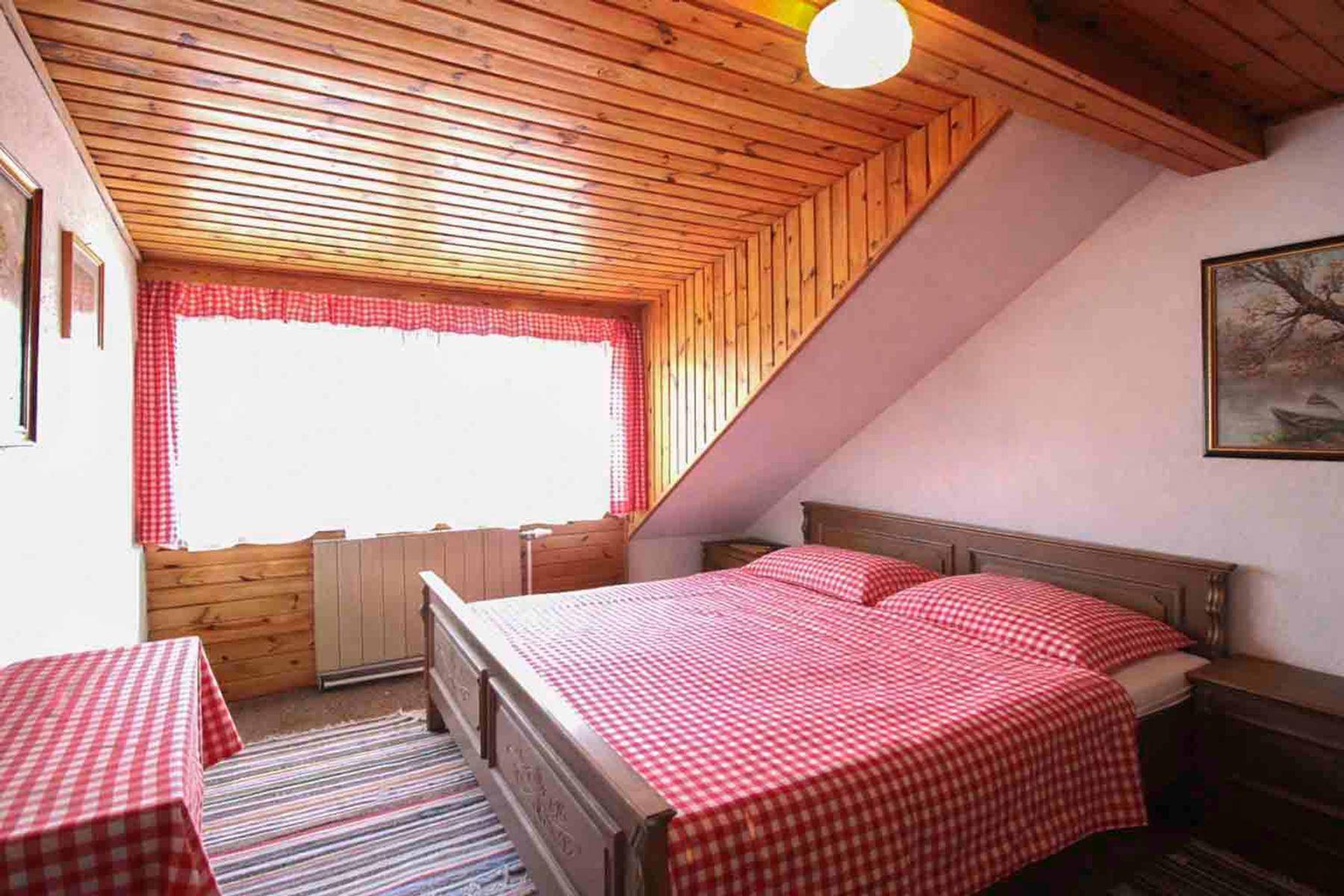 Gemütliches Schlafzimmer im Dachgeschoss mit Holzverkleidung, Dachschräge und Doppelbett.
