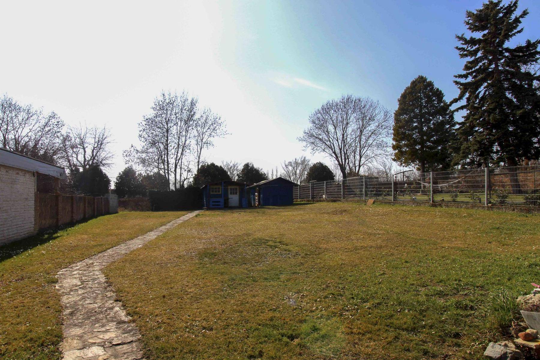 Großer, gepflegter Garten mit Rasenfläche, Bäumen und Gartenhütte im Hintergrund.