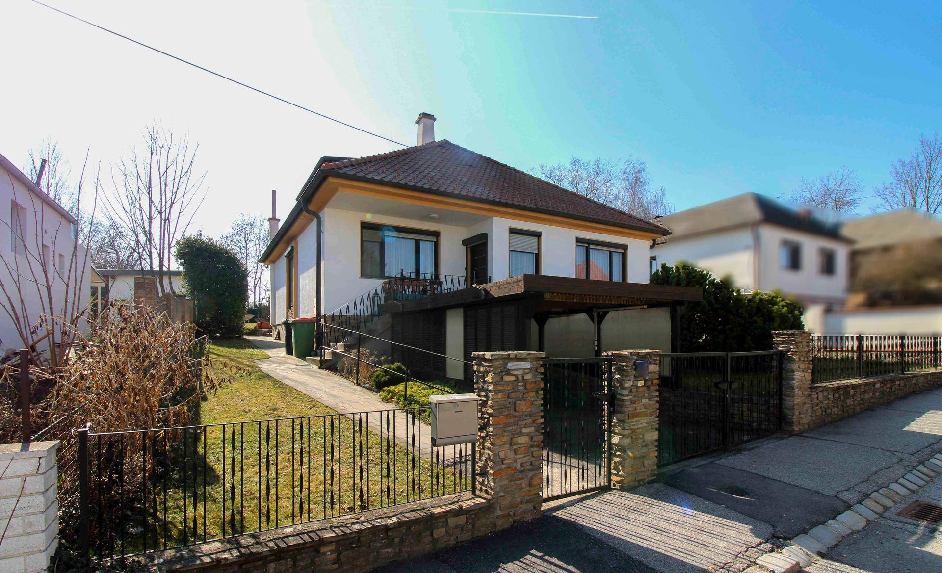 Einfamilienhaus mit Satteldach, Vorgarten und Zufahrt von der Straße.
