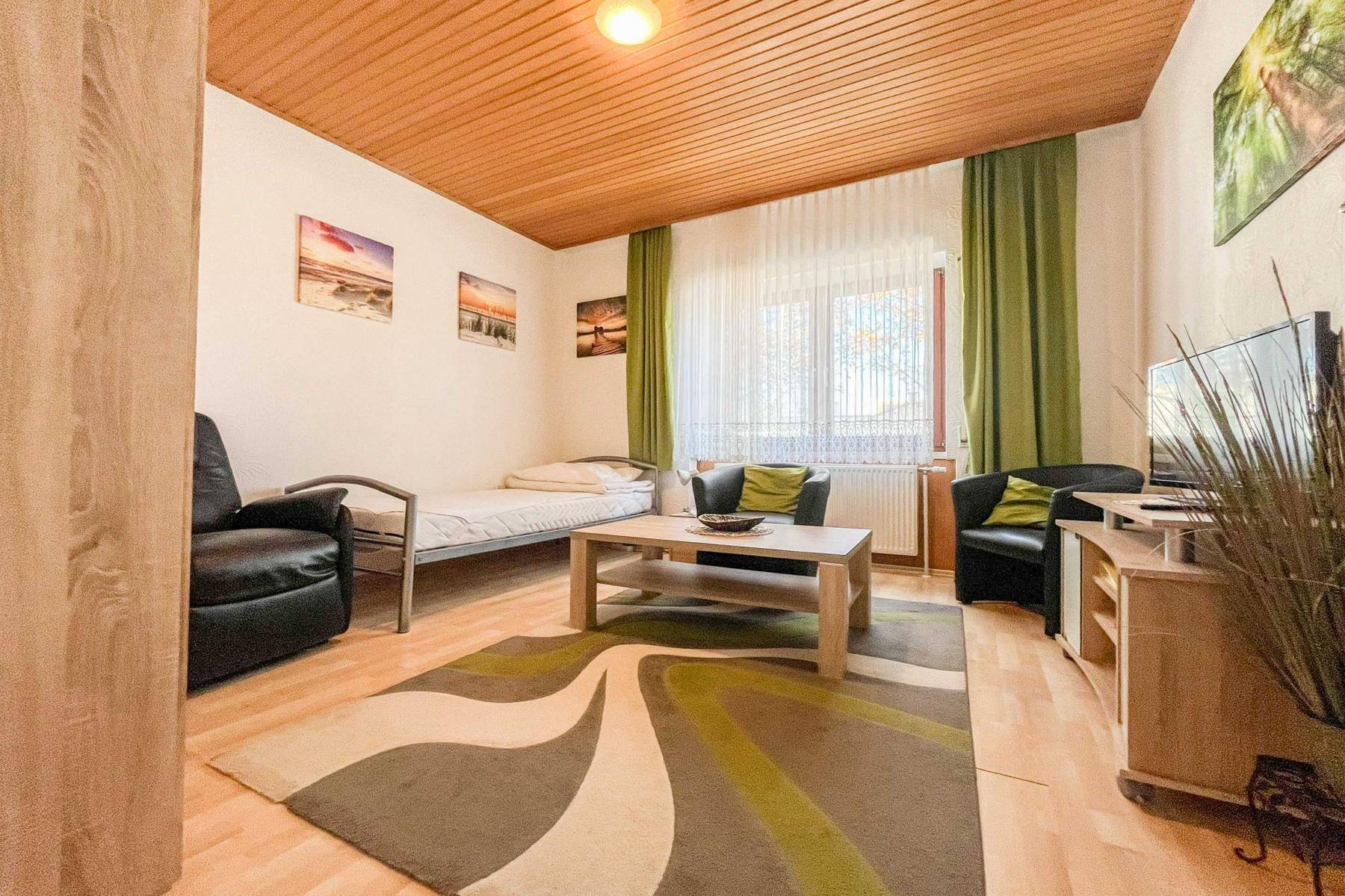 Gemütliches Schlafzimmer mit Holzdecke, Einzelbett und Teppichboden, ideal als Gästezimmer.
