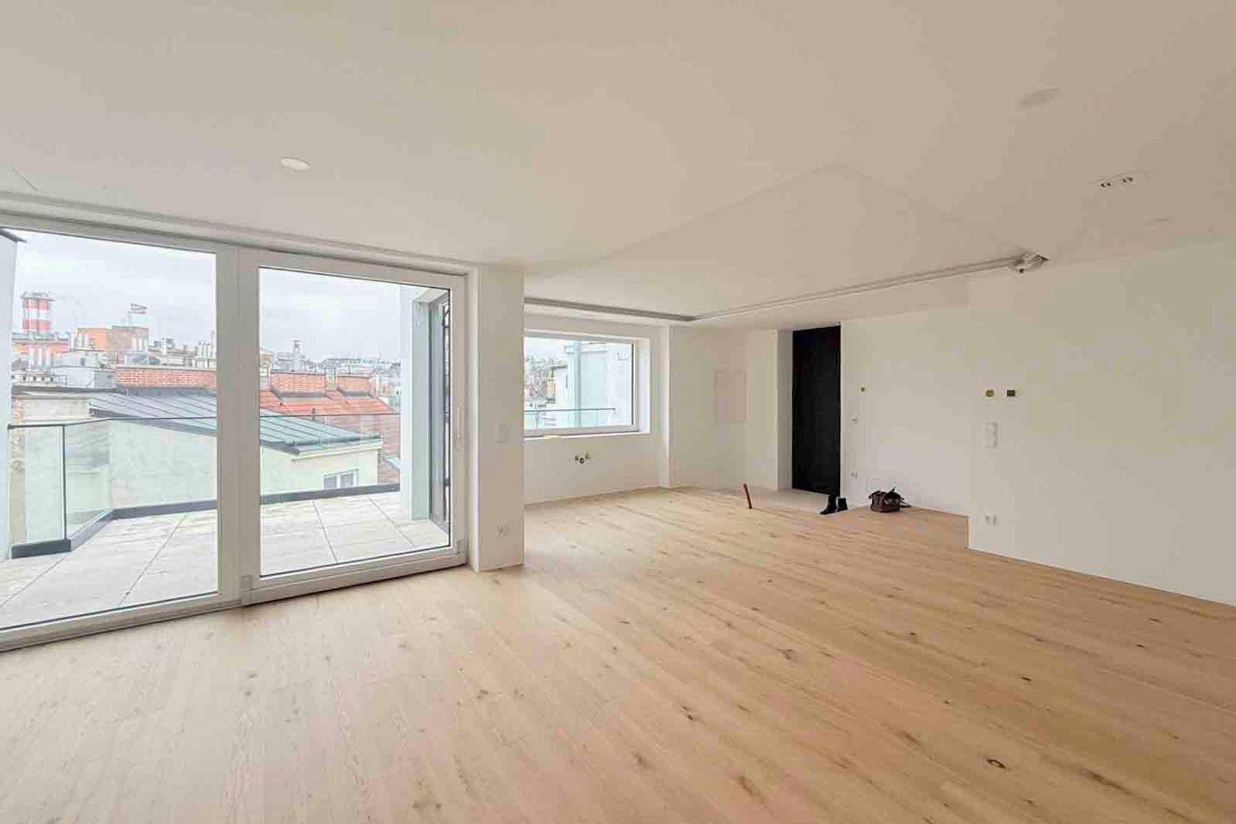Geräumiges, helles Wohnzimmer mit Holzboden und Zugang zu einer großen Terrasse.