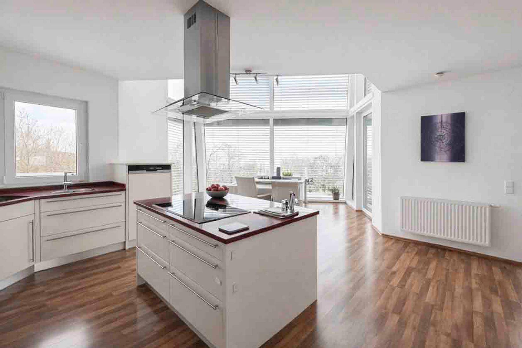 Moderne Küche mit Kochinsel, roten Arbeitsplatten und großen Fenstern mit weitem Ausblick.