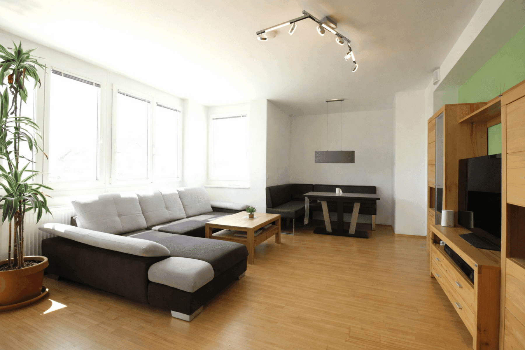 Heller Wohn-Essbereich mit Parkettboden, großem Sofa und Essbereich mit Eckbank.