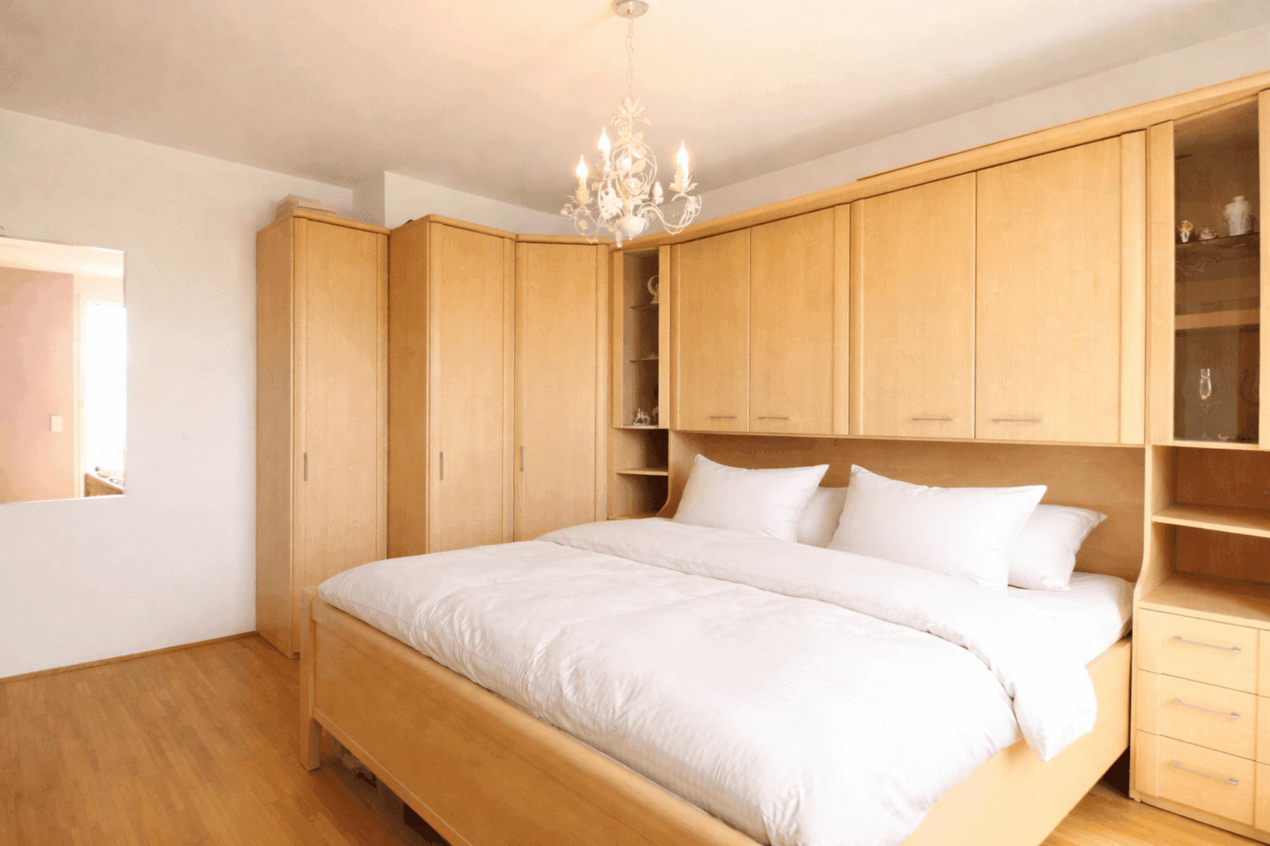 Helles Schlafzimmer mit Einbauschränken aus hellem Holz und Parkettboden.