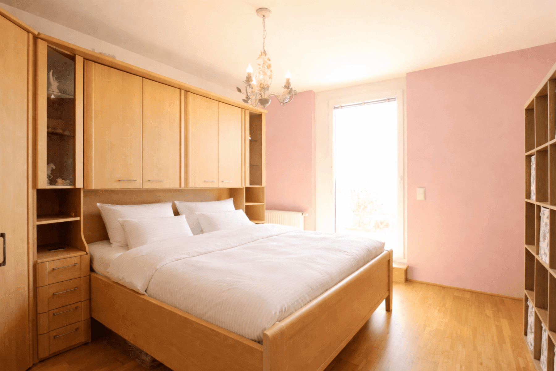 Schlafzimmer mit hellem Parkettboden, Einbauschränken und Fenster mit viel Tageslicht.