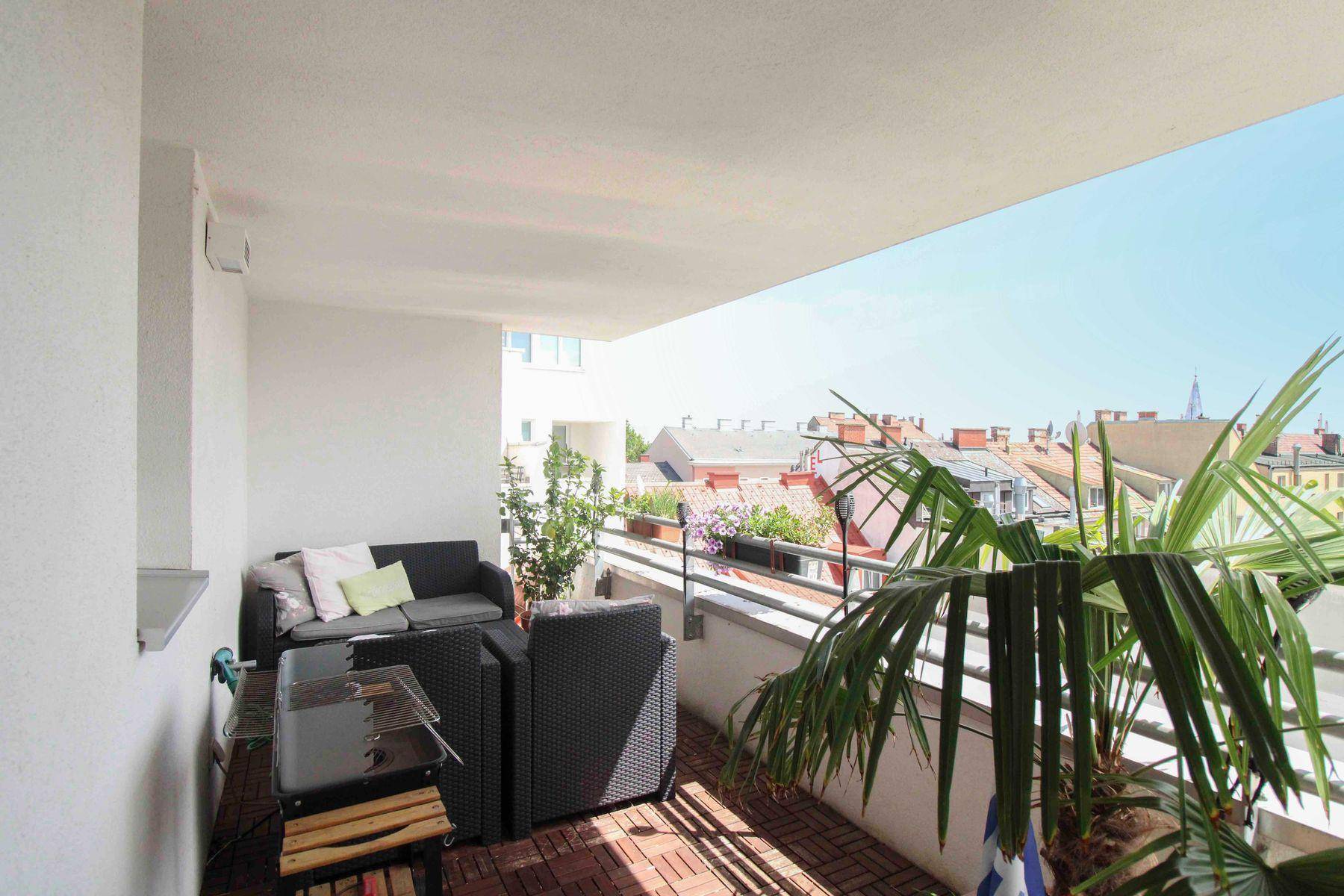 Geräumiger Balkon mit bequemen Loungemöbeln und Blick über die Dächer der Stadt.