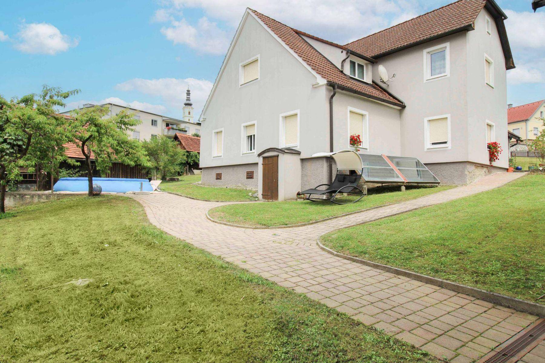 Seitenansicht des Hauses mit gepflastertem Weg, aufblasbarem Pool und Solarkollektoren.