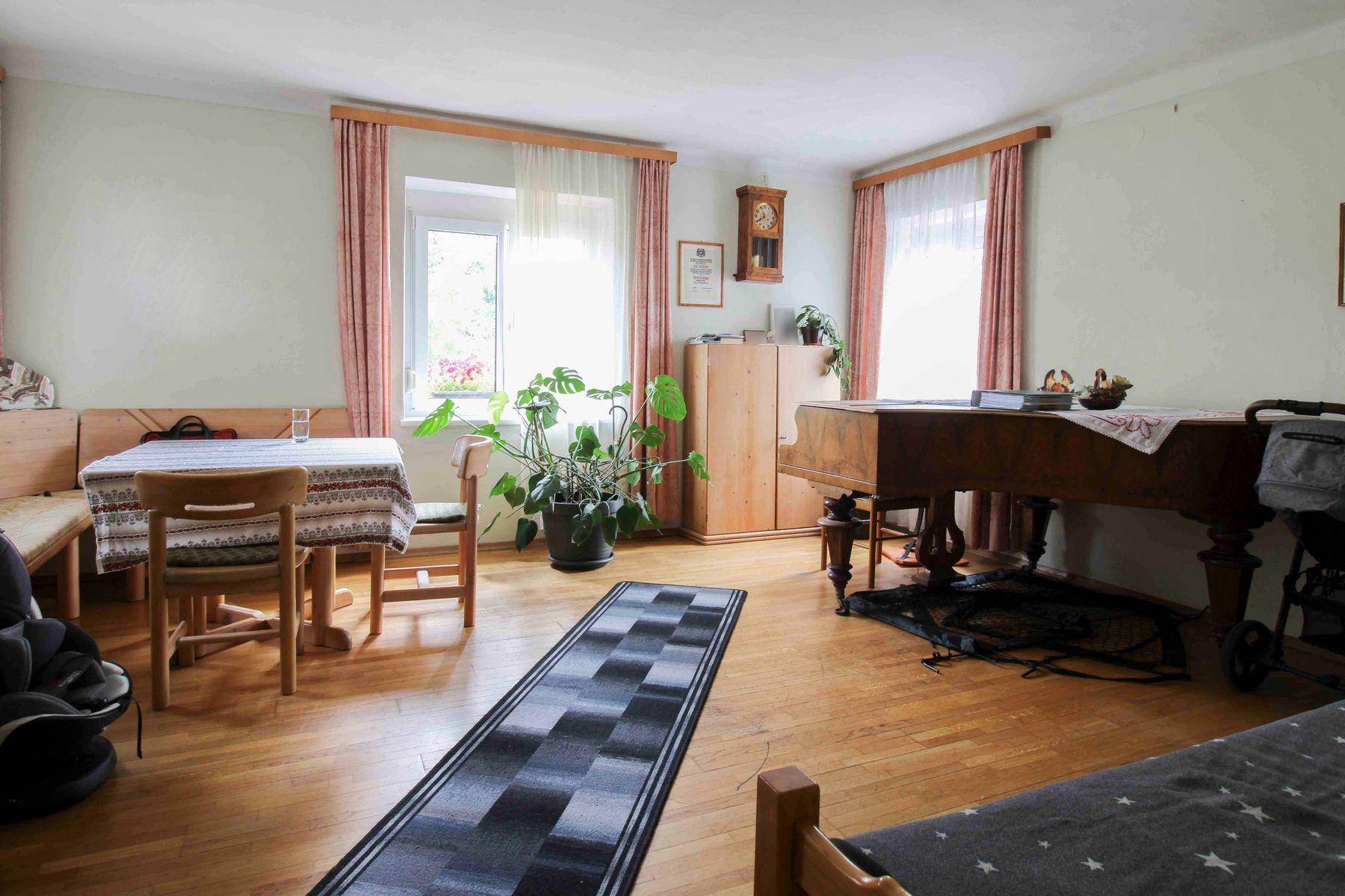 Gemütlicher Wohnbereich mit Esstisch, Holzparkett und einem klassischen Klavier, ideal für Familienleben.