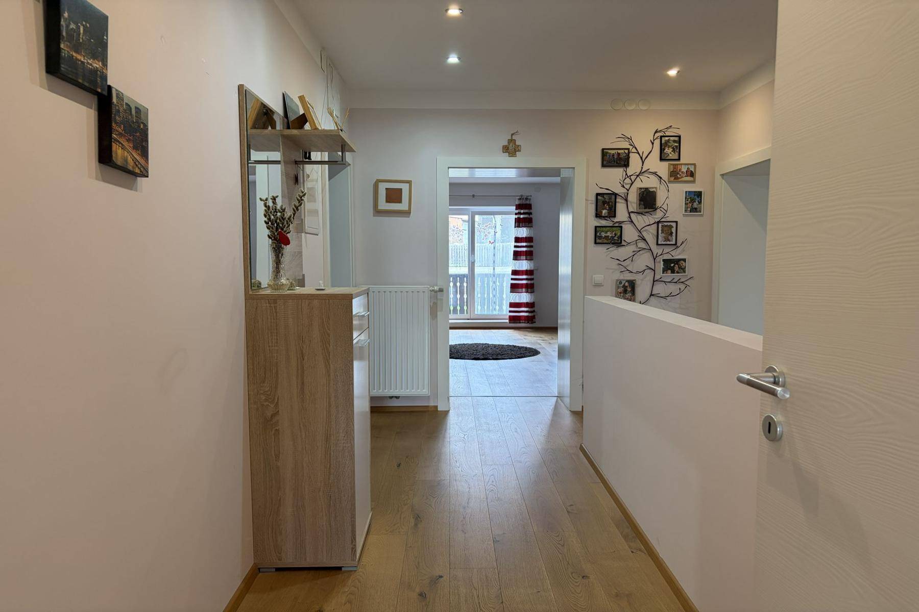 Heller Flur mit Holzparkett, Garderobe und offenem Blick in den angrenzenden Wohnbereich.