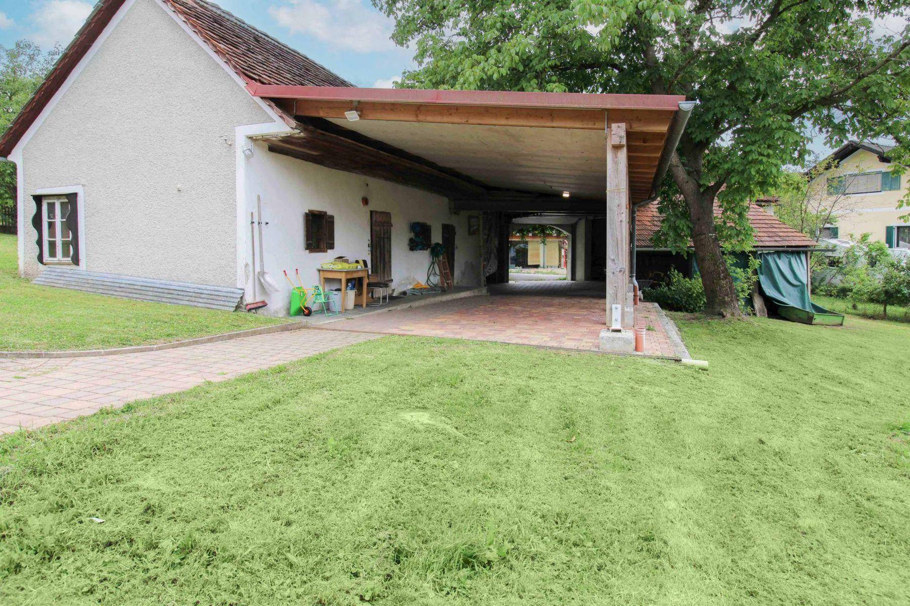 Überdachter Bereich neben dem Haus, nutzbar als Carport oder Abstellfläche, mit gepflastertem Zugang.