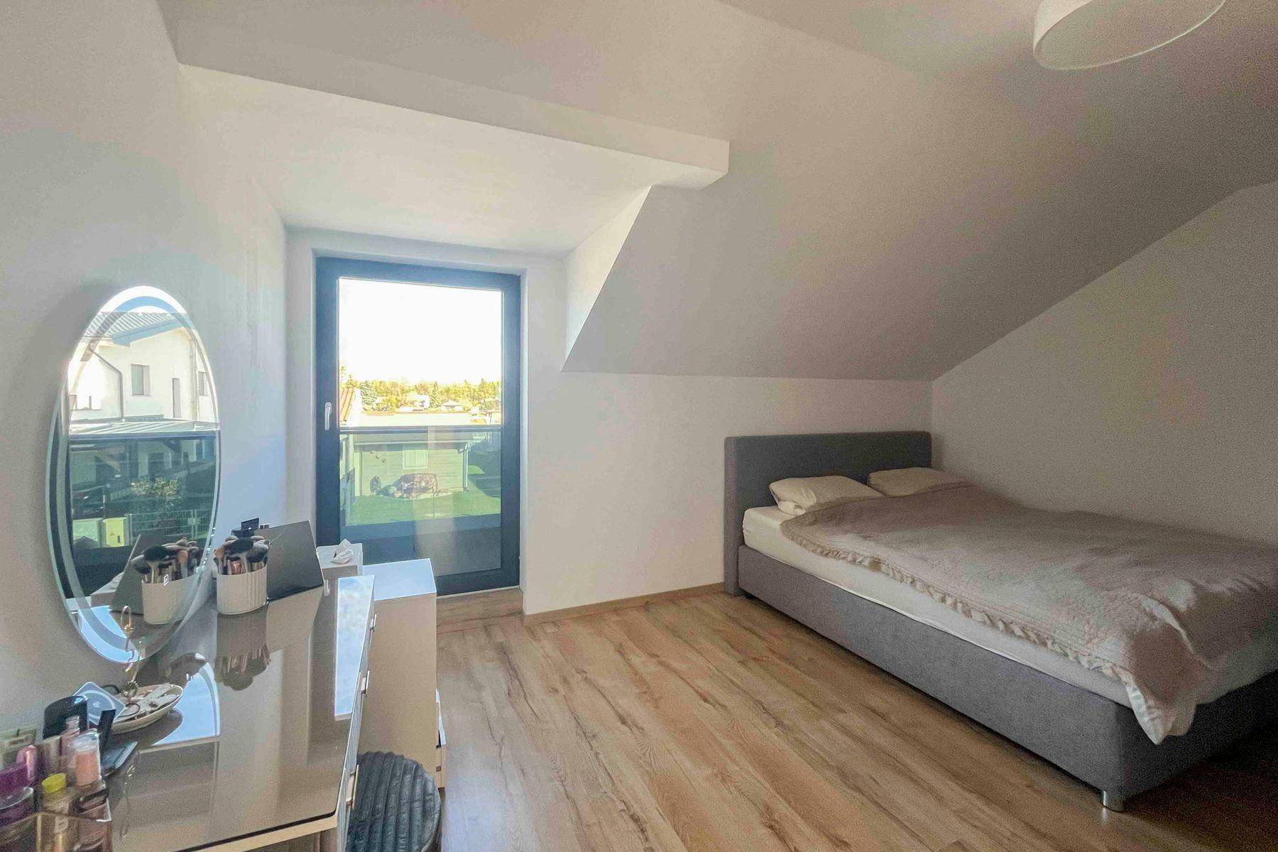 Helles Schlafzimmer mit Holzboden, Schminktisch und Fenster mit Ausblick.