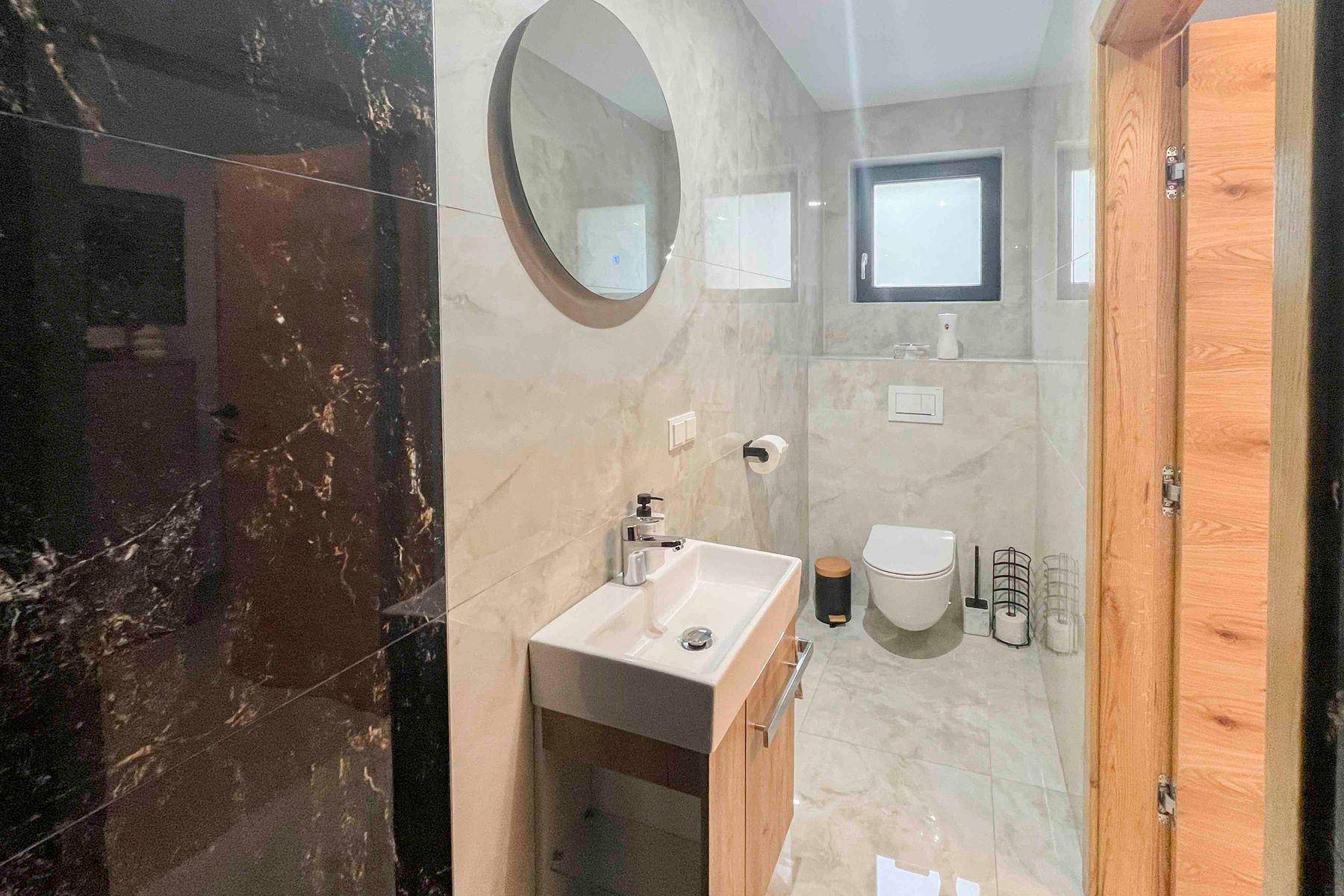 Modernes Gäste-WC mit Wand-WC, Einzelwaschbecken und Fenster für Tageslicht.