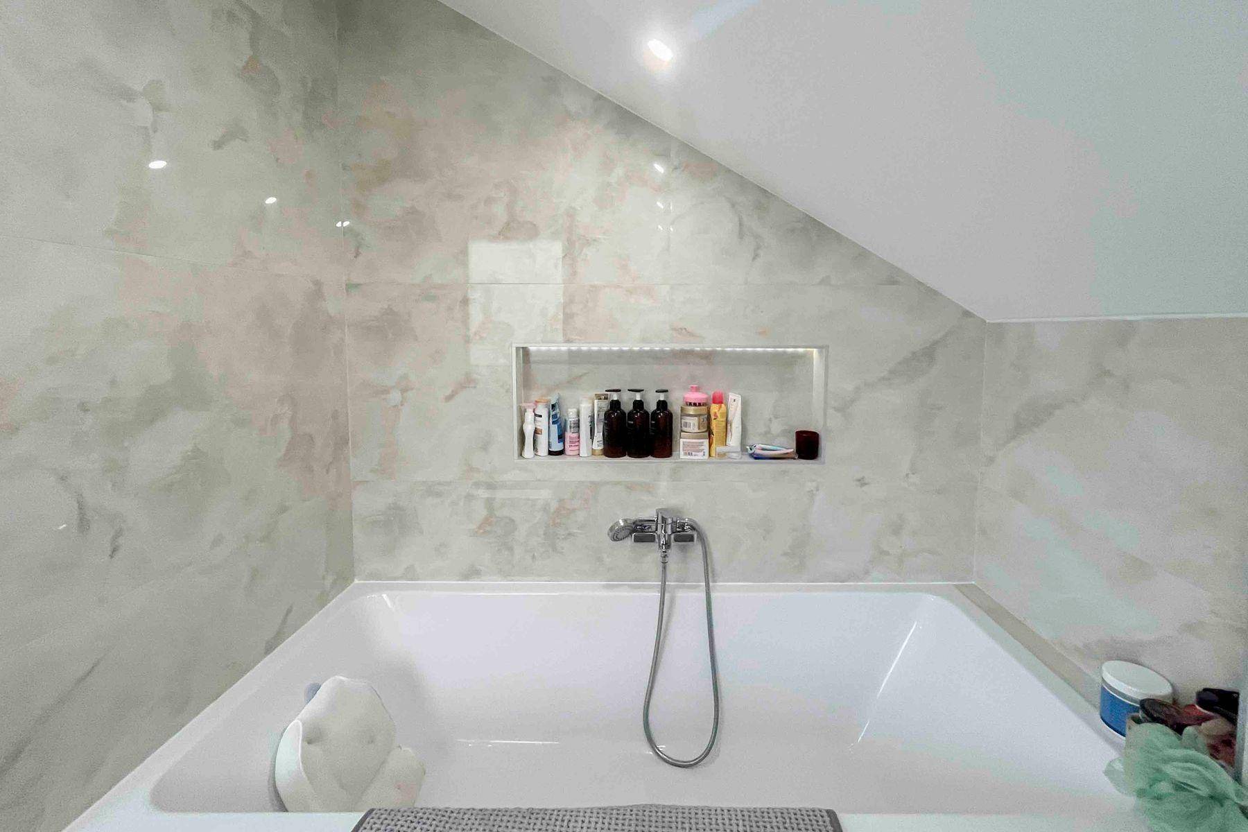 Modernes Badezimmer mit eingebauter Badewanne und eleganten Marmorfliesen.