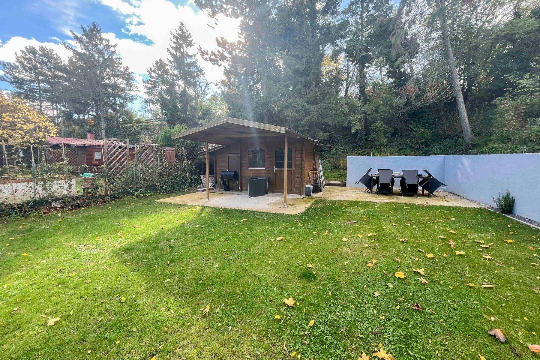 Gartenbereich mit Holzschuppen, überdachtem Grillplatz und weiteren Sitzgelegenheiten.