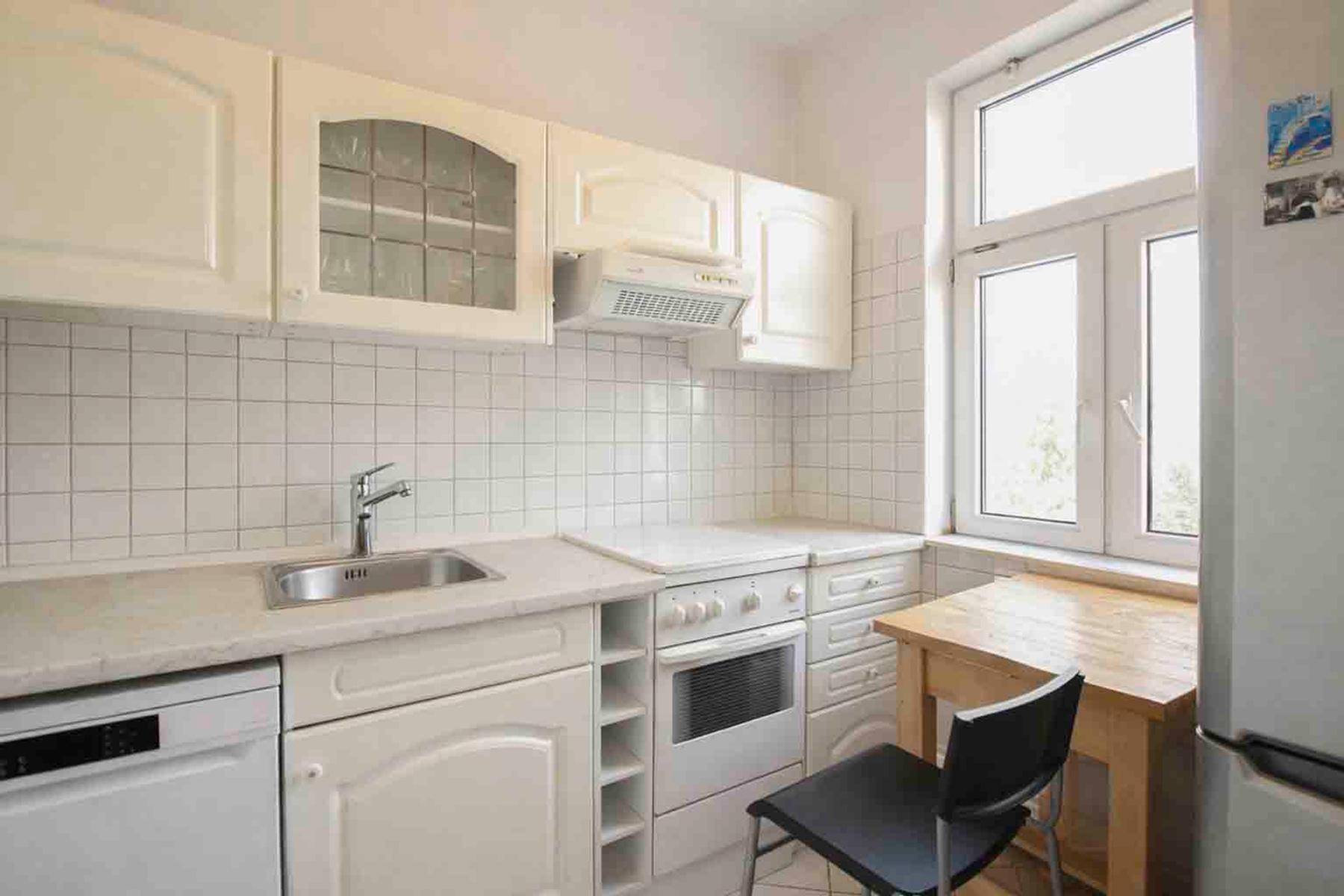 Helle Küche mit weißen Schränken, Fliesenrückwand und einem Fenster.