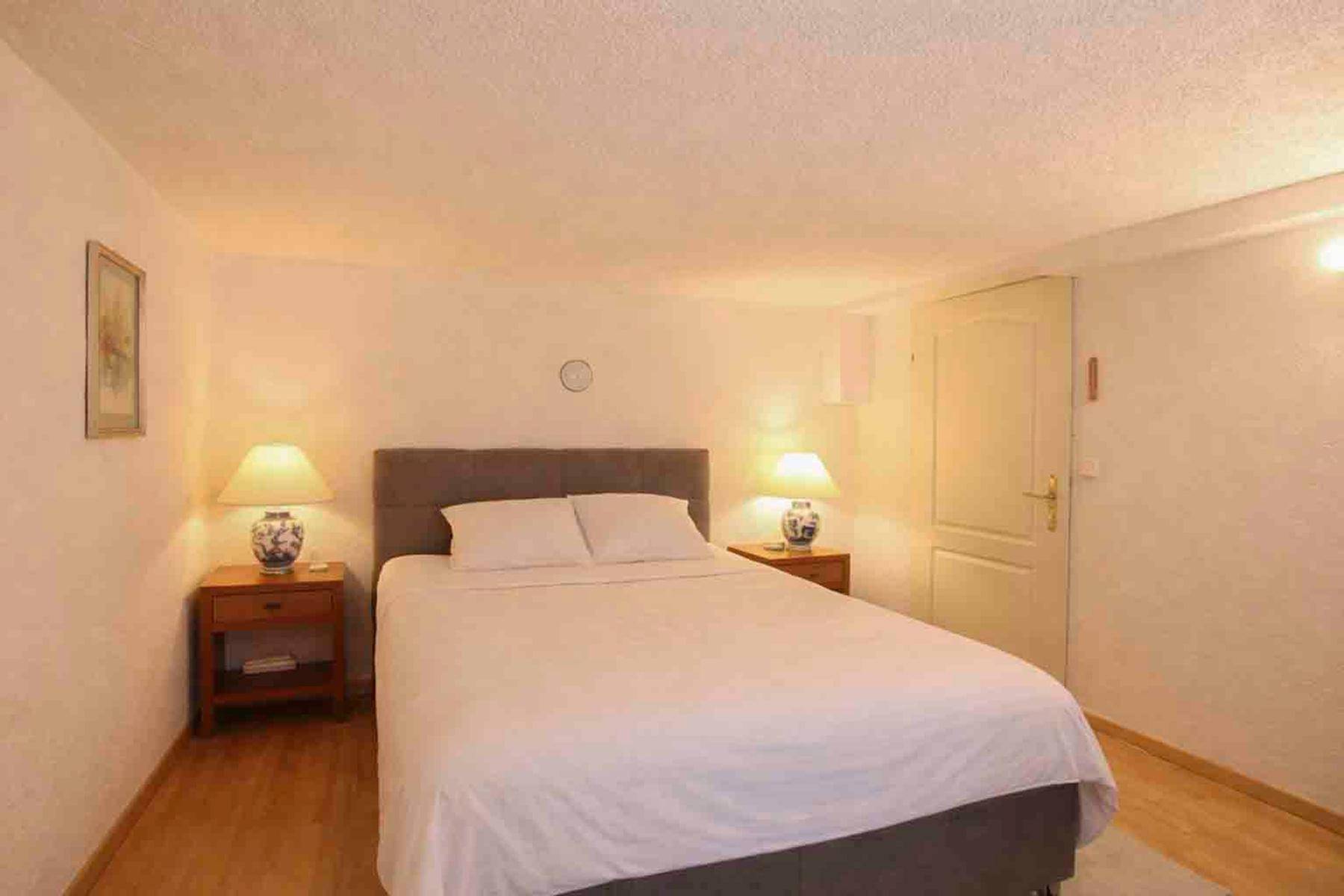 Gemütliches Schlafzimmer mit Doppelbett, Nachttischen und Holzboden.