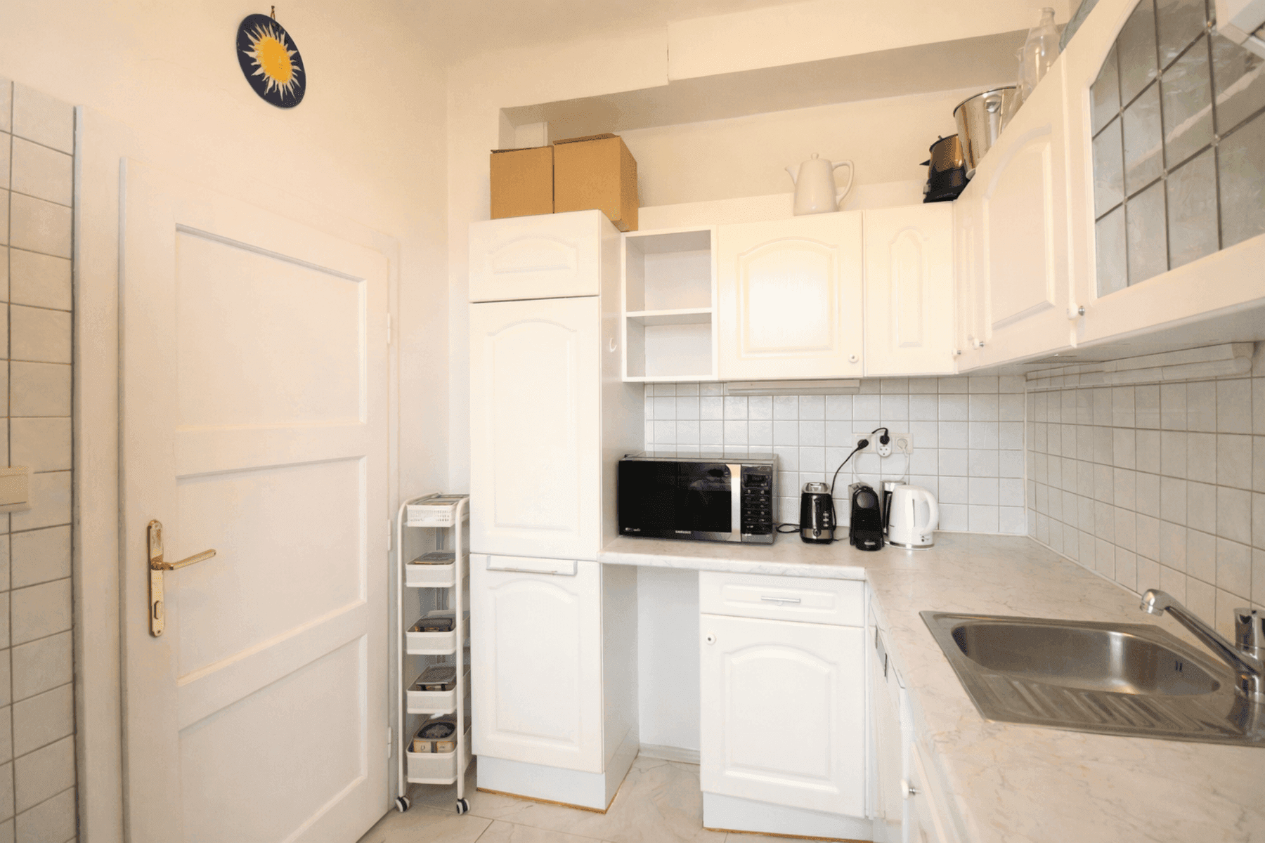 Funktionale Küche mit weißen Schränken, Mikrowelle und Fliesenrückwand.