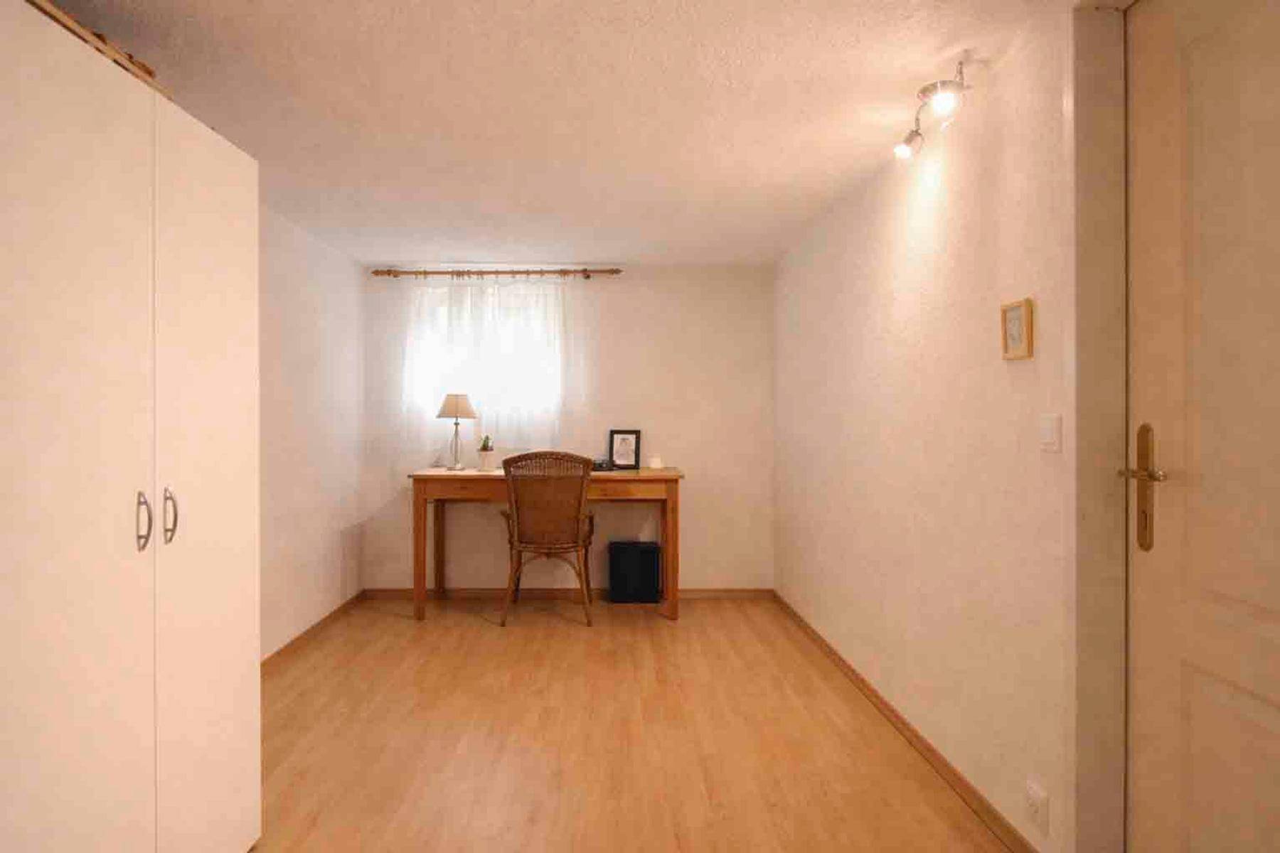 Helles Arbeitszimmer mit Holzboden, Schreibtisch und einem Fenster.