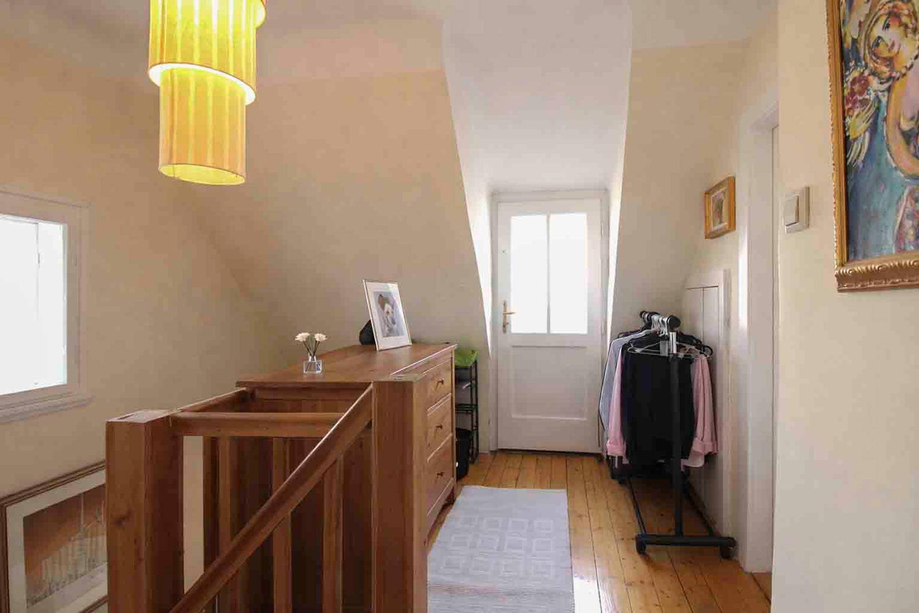Heller Flur im Dachgeschoss mit Holztreppe, Dachschräge und Holzboden.
