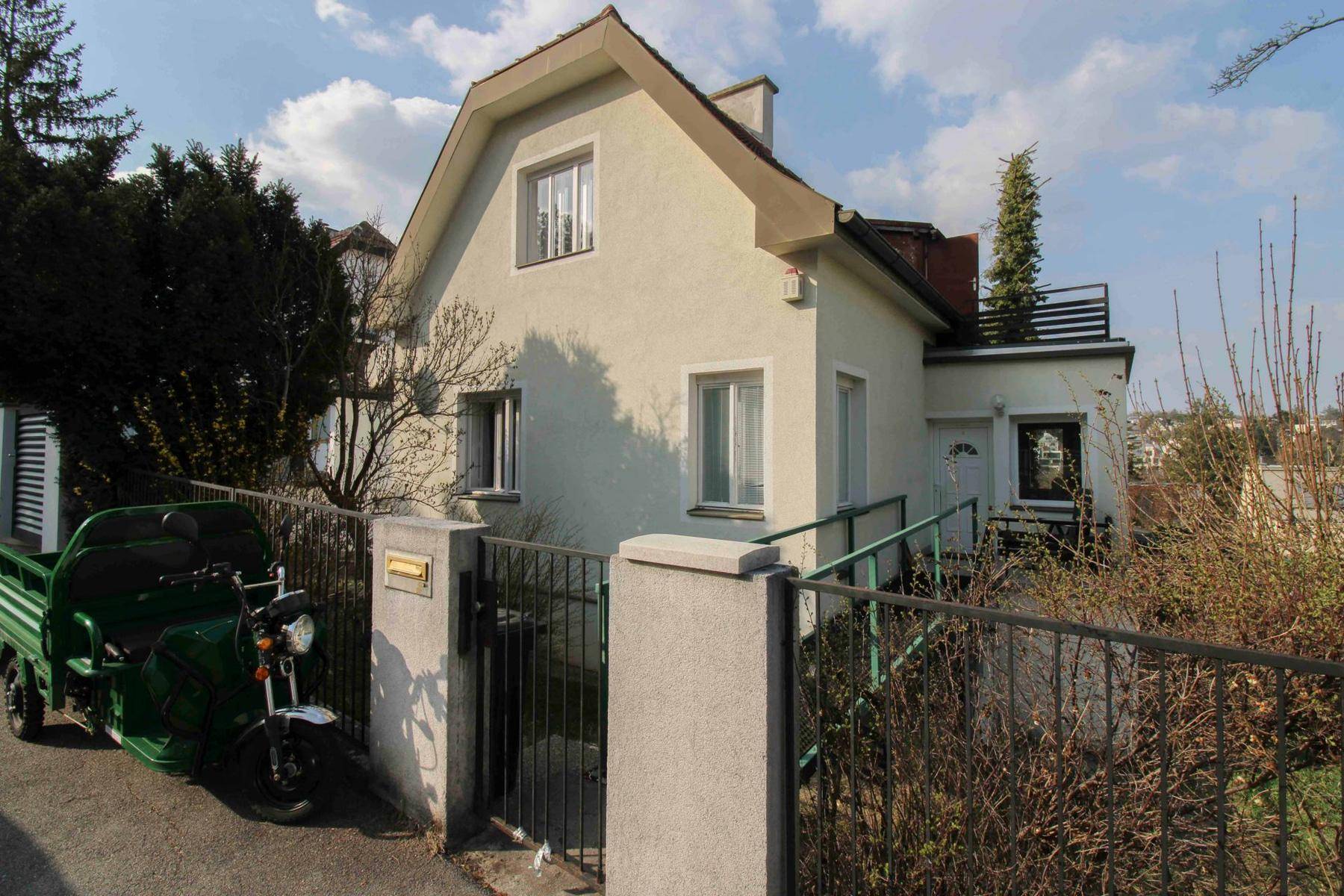 Vorderansicht des Hauses mit Zaun, Auffahrt und einem kleinen Vorgarten.
