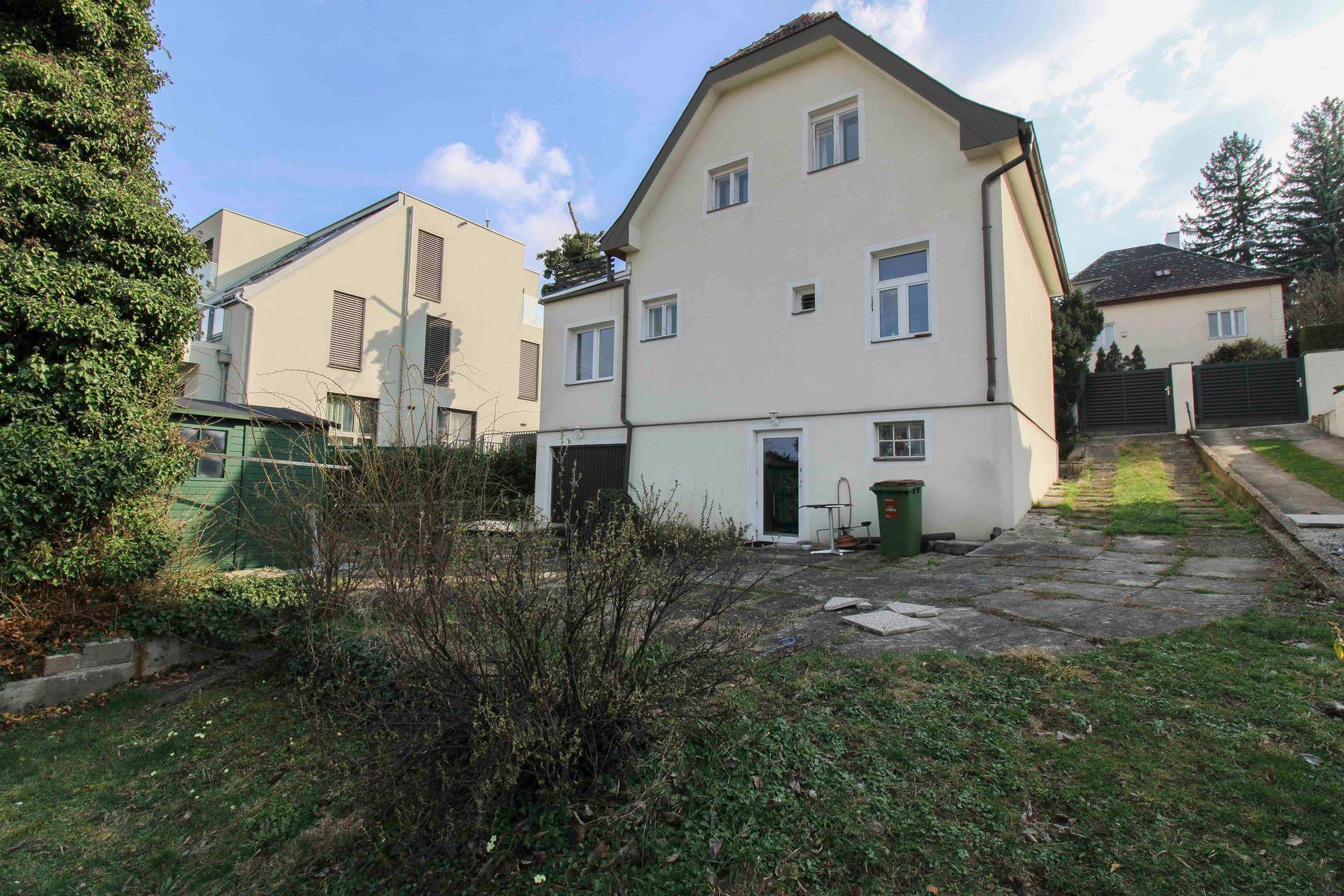 Hinterhof mit Rasenfläche, Gartenhaus und der Rückseite des Hauses.