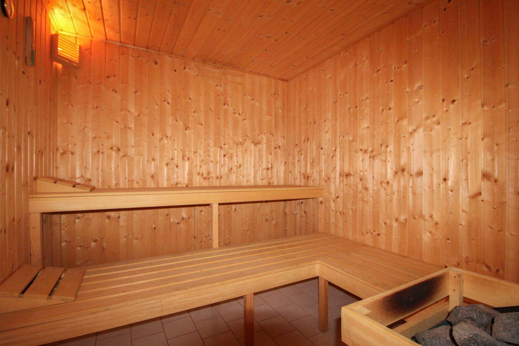 Traditionelle Holzsauna mit Sitzbänken und Saunaofen für entspannende Momente.