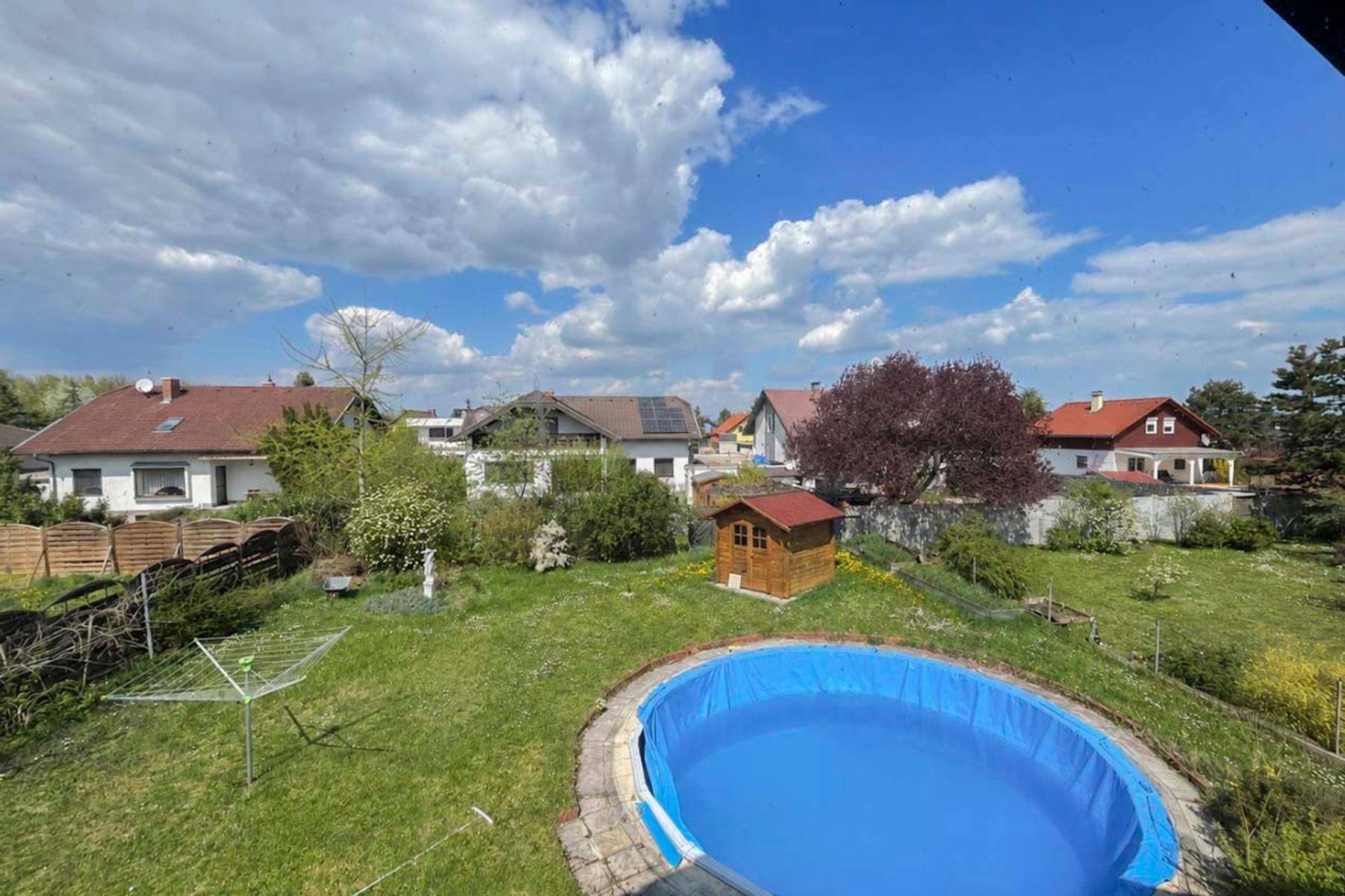 Großer Garten mit Pool, Gartenhaus und Wäscheleine, umgeben von viel Grün.