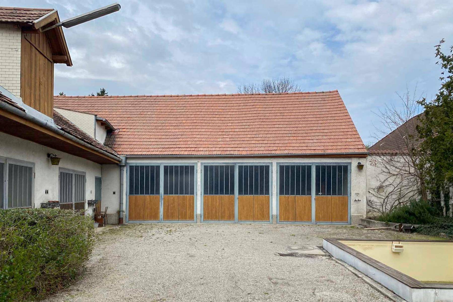 Außenansicht eines Gebäudes mit mehreren Garagentoren und einem Ziegeldach.