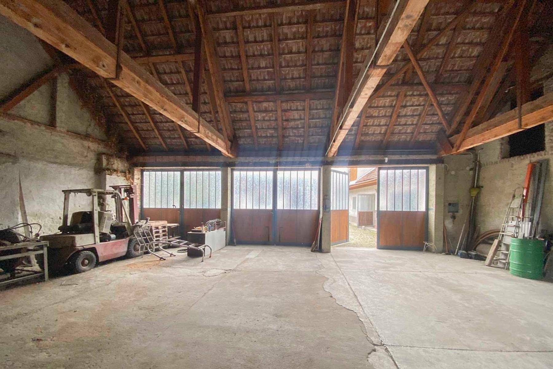 Geräumiger Innenraum einer Scheune oder Garage mit hohen Holzdecken und Betonboden.